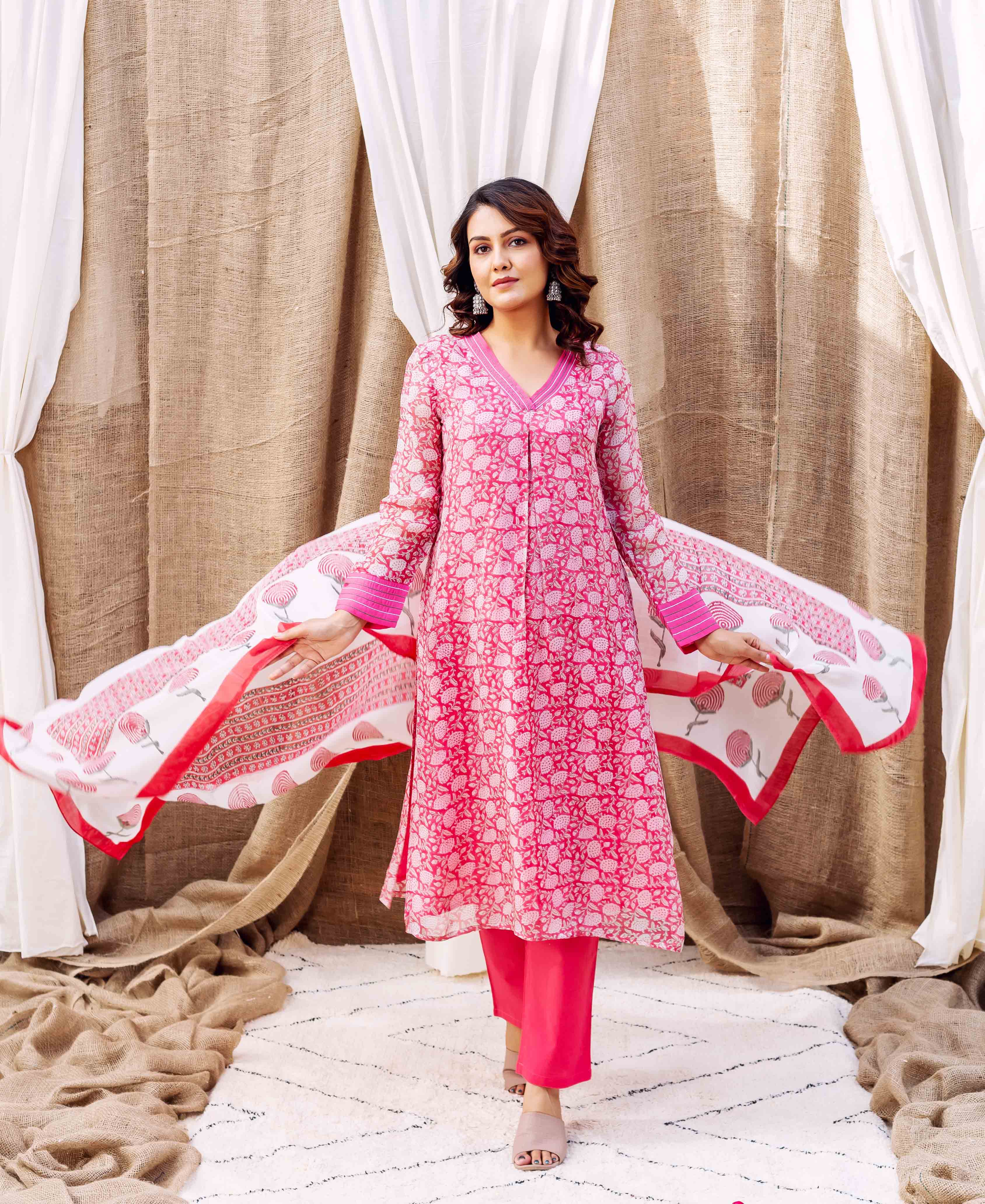 Model poses in pink kurta, showcasing a flowing white dupatta with red hand-printed floral patterns.