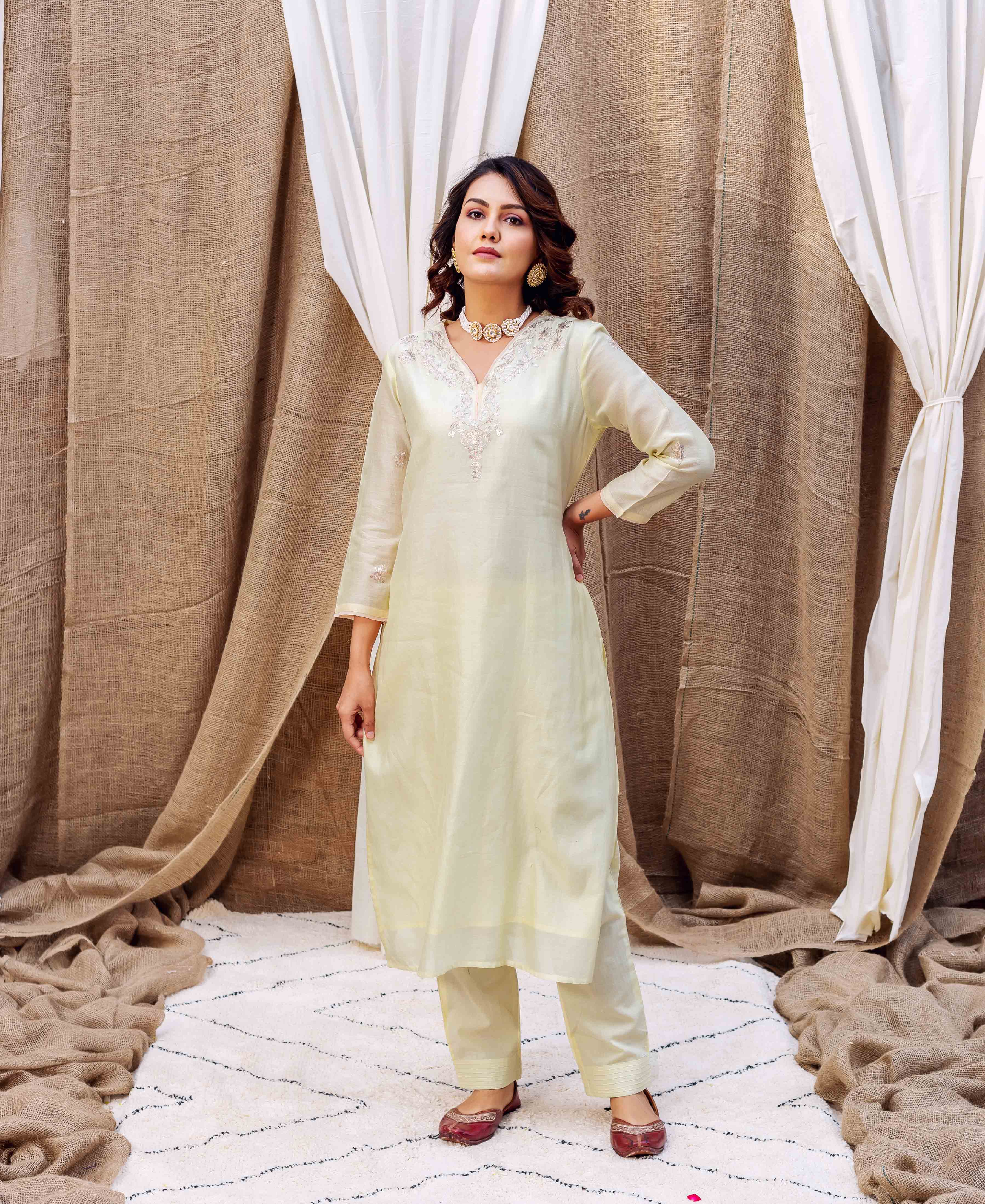Full-length shot of a model wearing a light yellow kurta set with delicate white embroidery.