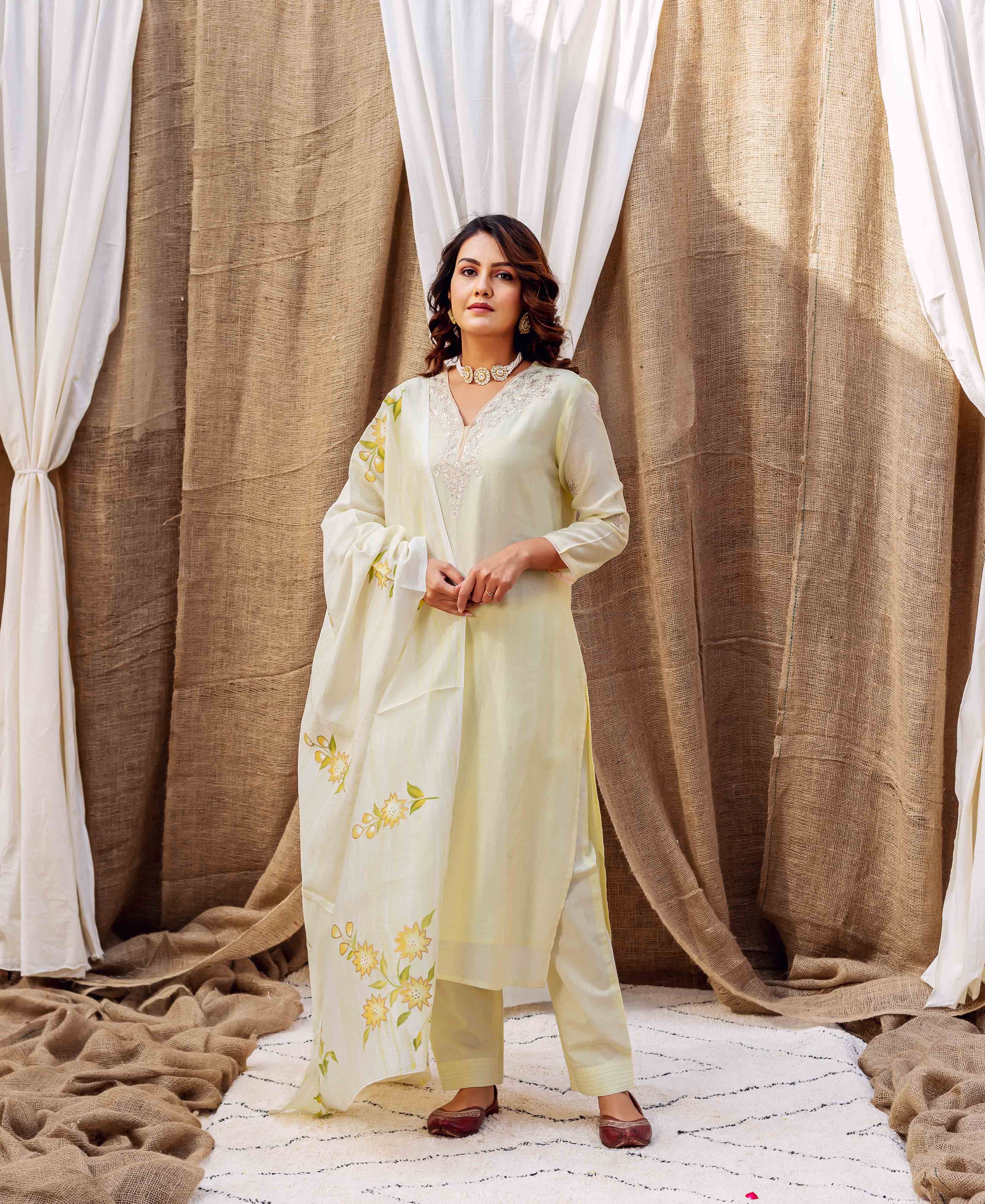 Woman in light yellow kurta set with white embroidery and yellow floral printed dupatta.