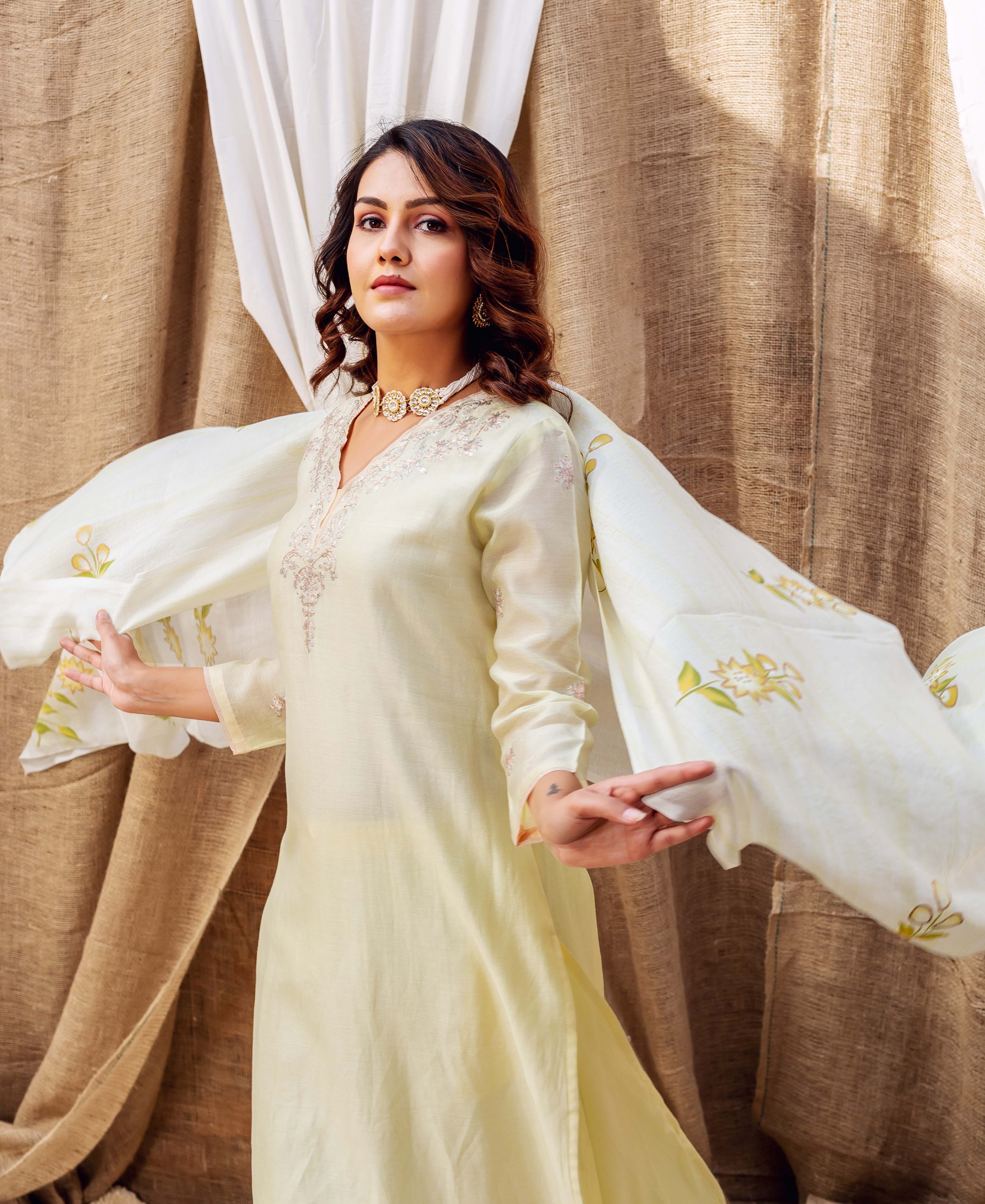 Model wearing a light yellow kurta and a hand-block printed floral dupatta, flowing dynamically.