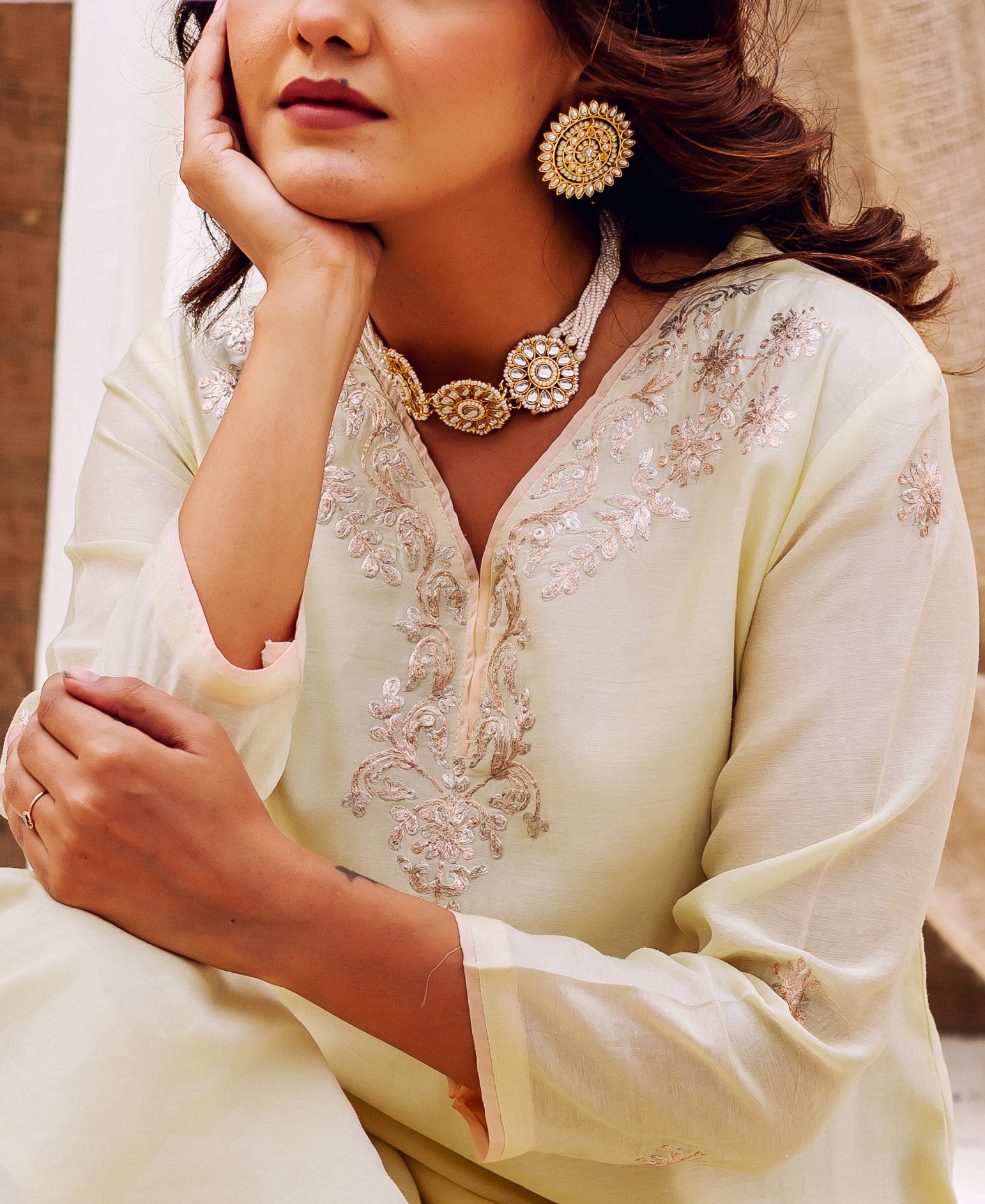 Model close-up in pale yellow kurta with intricate Pittan work embroidery and statement jewelry.