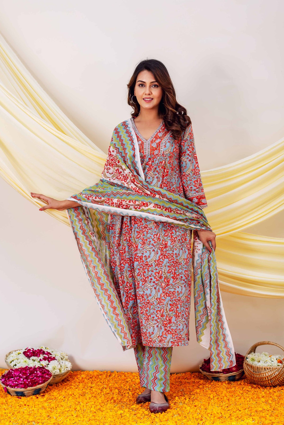 Woman wearing red, blue and yellow hand-block-printed kurta and pants with floral and zigzag pattern.