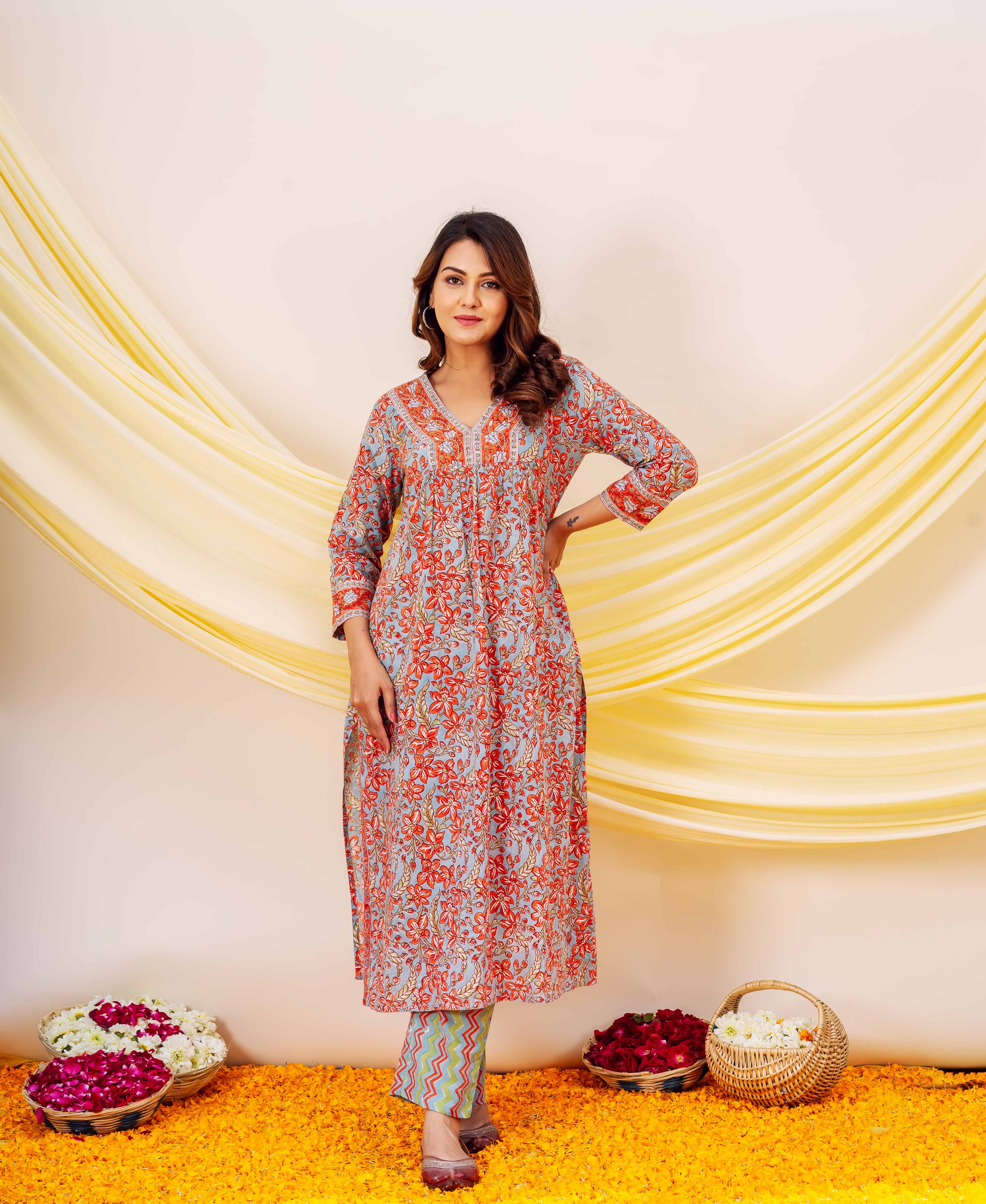 Woman wears a long grey kurta with red, gold floral hand block print and patterned pants.