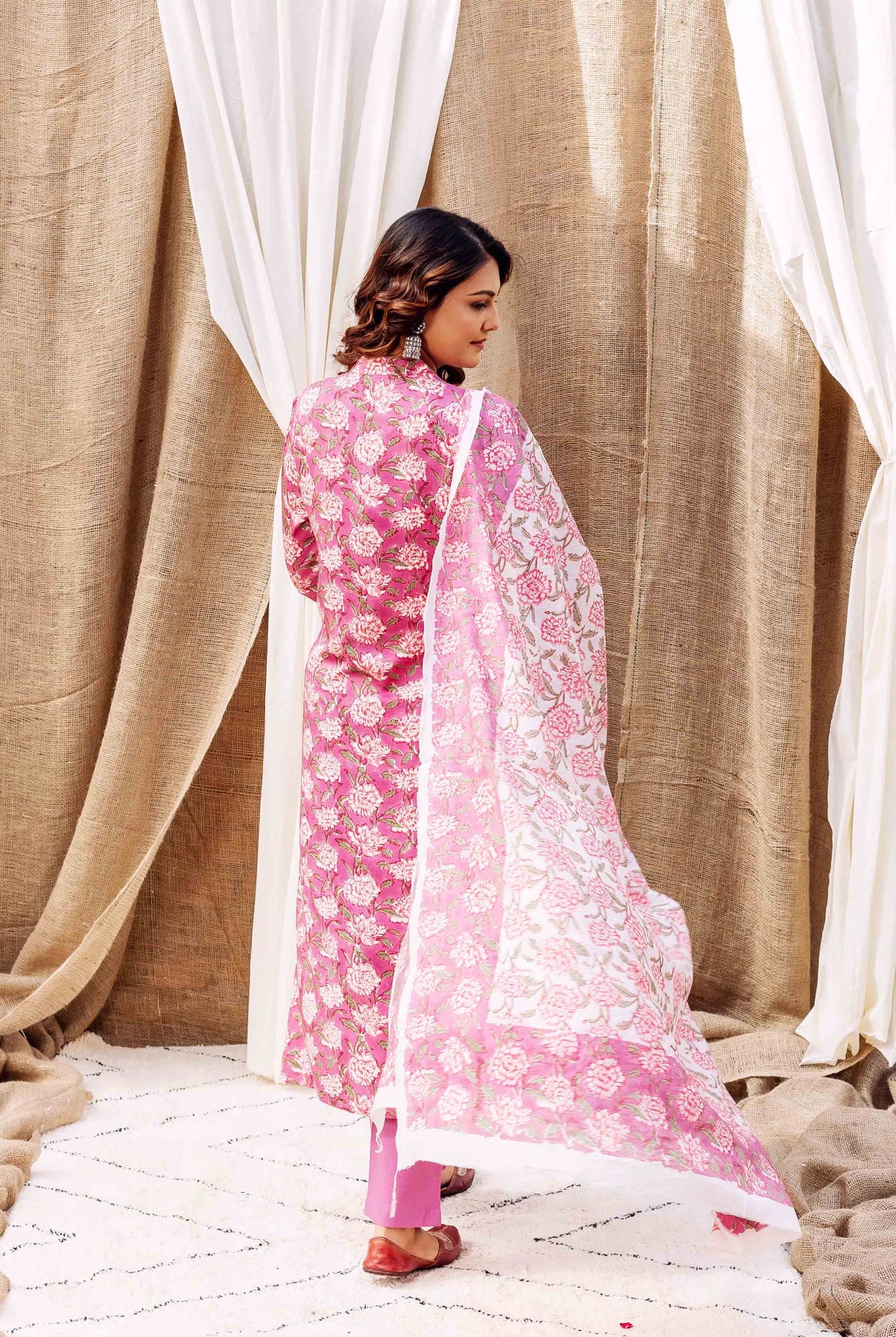 A woman in a pink floral kurta with a matching dupatta.