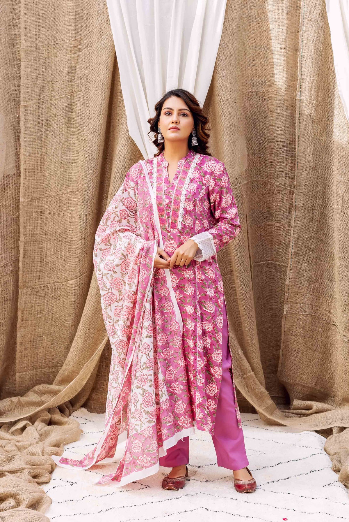 Model wearing a magenta floral hand-block-printed kurta set with matching dupatta.