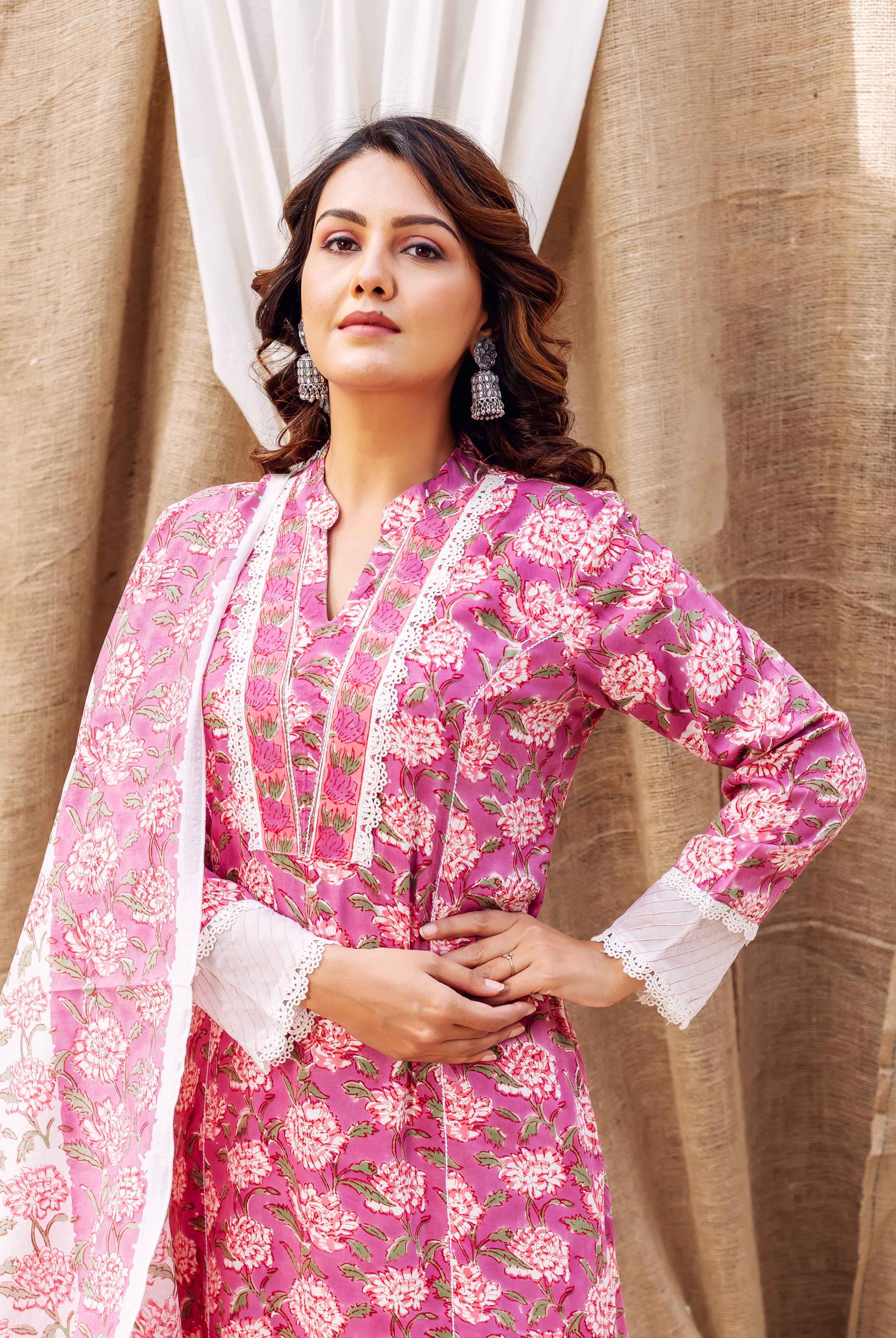 Woman in a vibrant pink hand-block-printed floral kurta with white lace and matching dupatta.