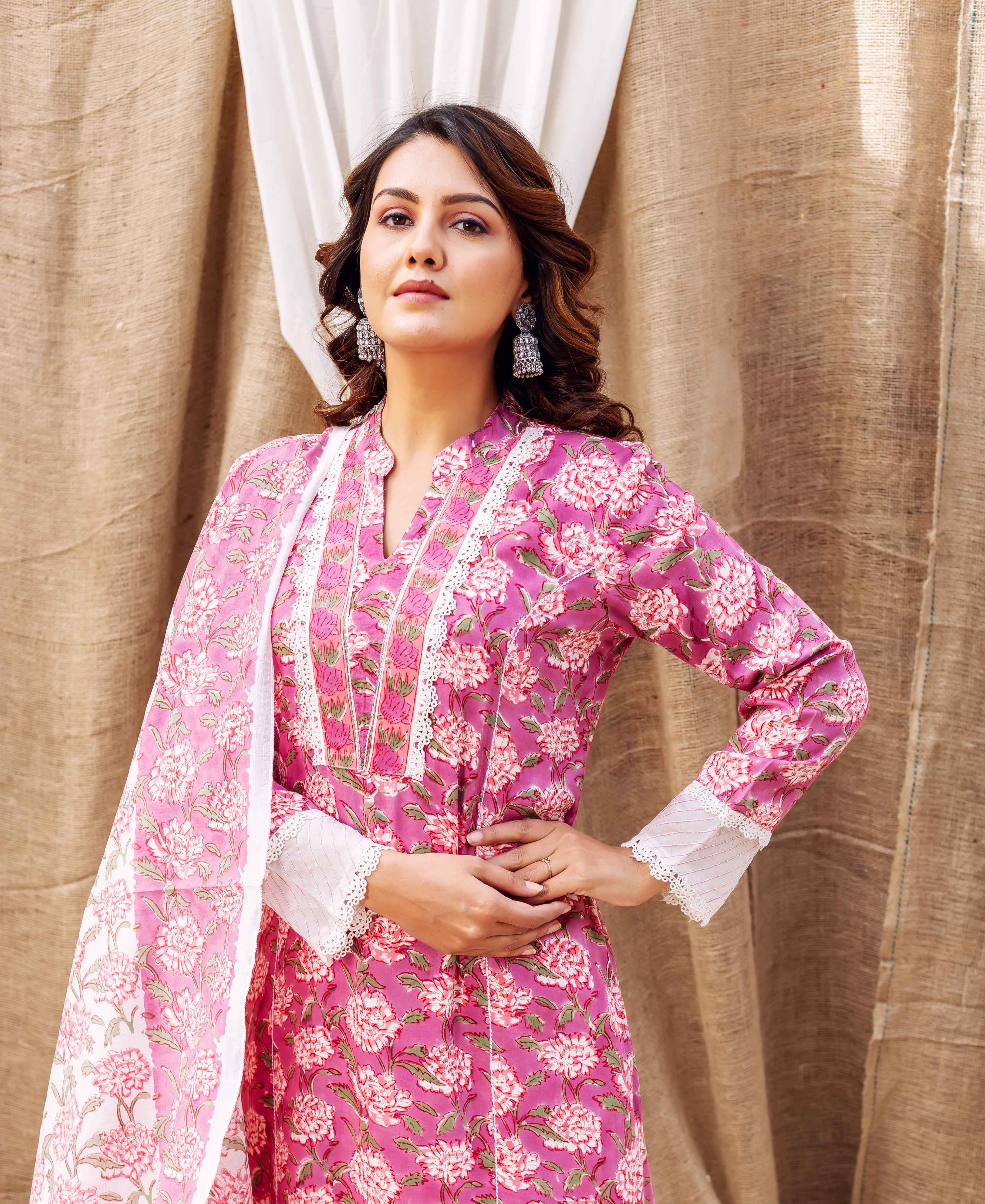 Woman in a vibrant pink hand-block-printed floral kurta with white lace and matching dupatta.