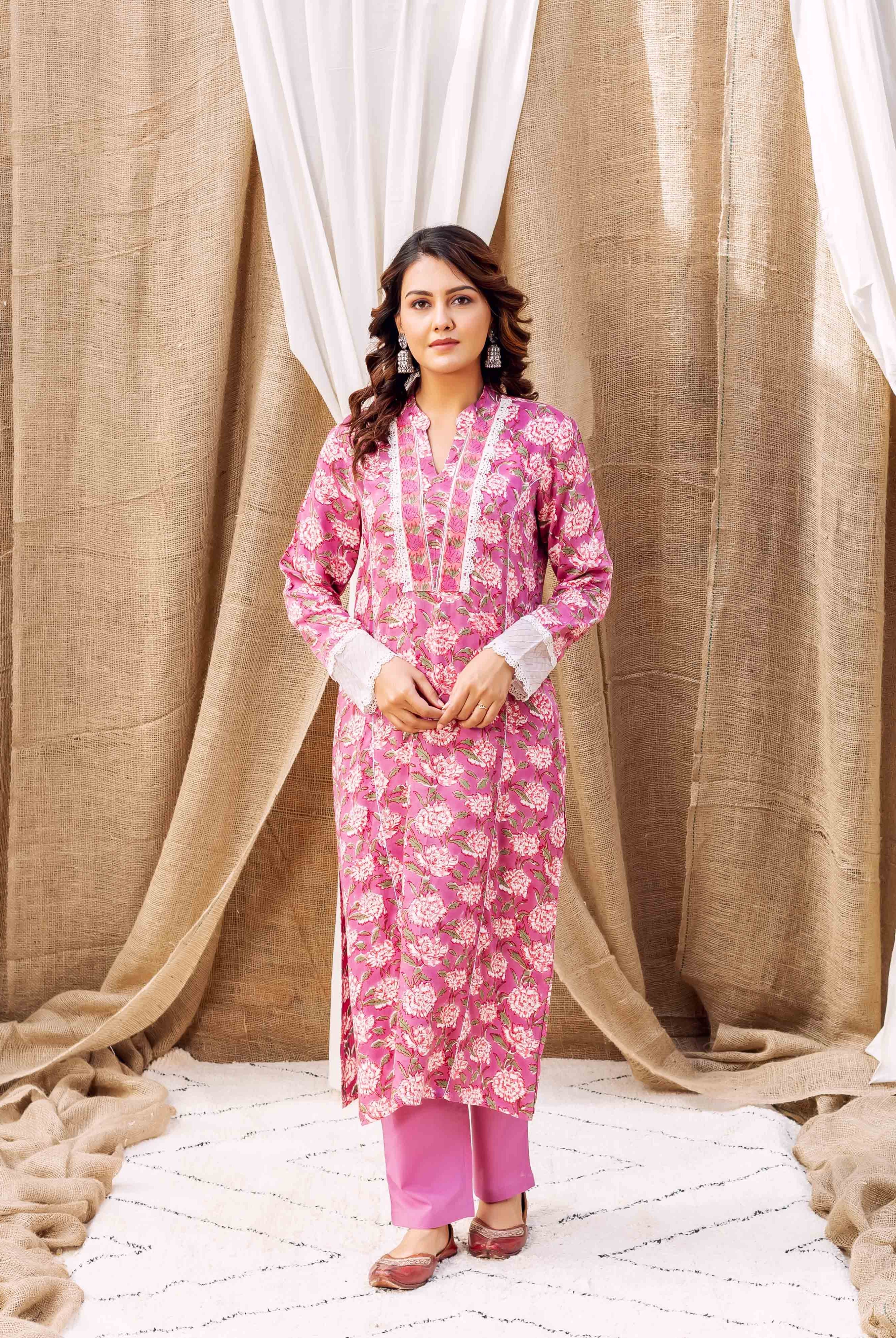 A woman in a pink floral kurta with white trim and pink pants.