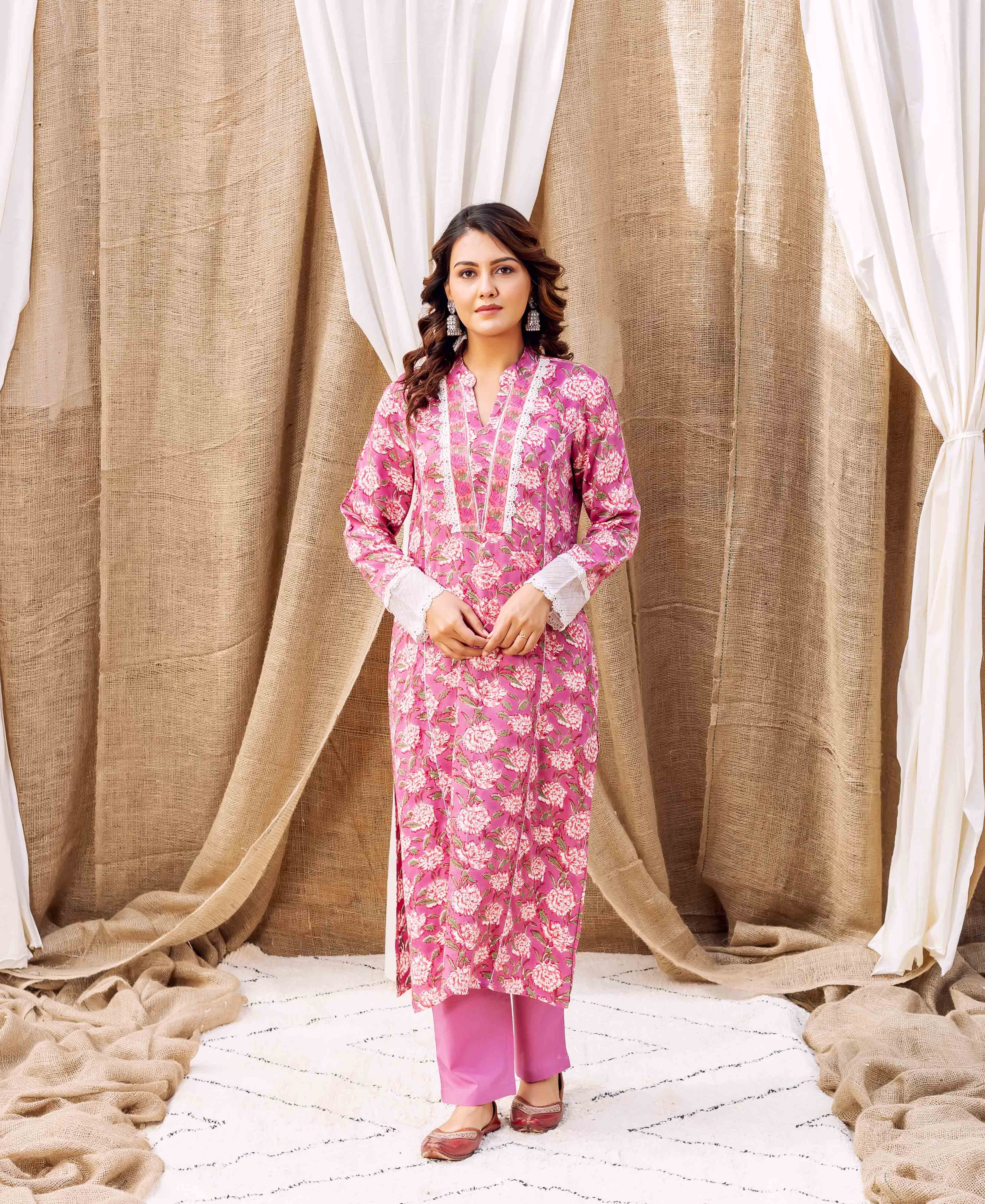 A woman in a pink floral kurta with white trim and pink pants.