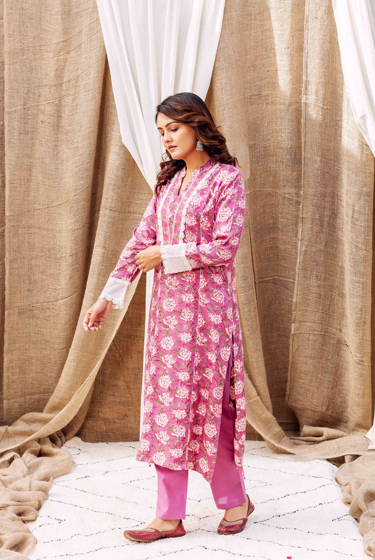 Model wearing a pink hand-block-printed floral kurta with white lace and matching pants.