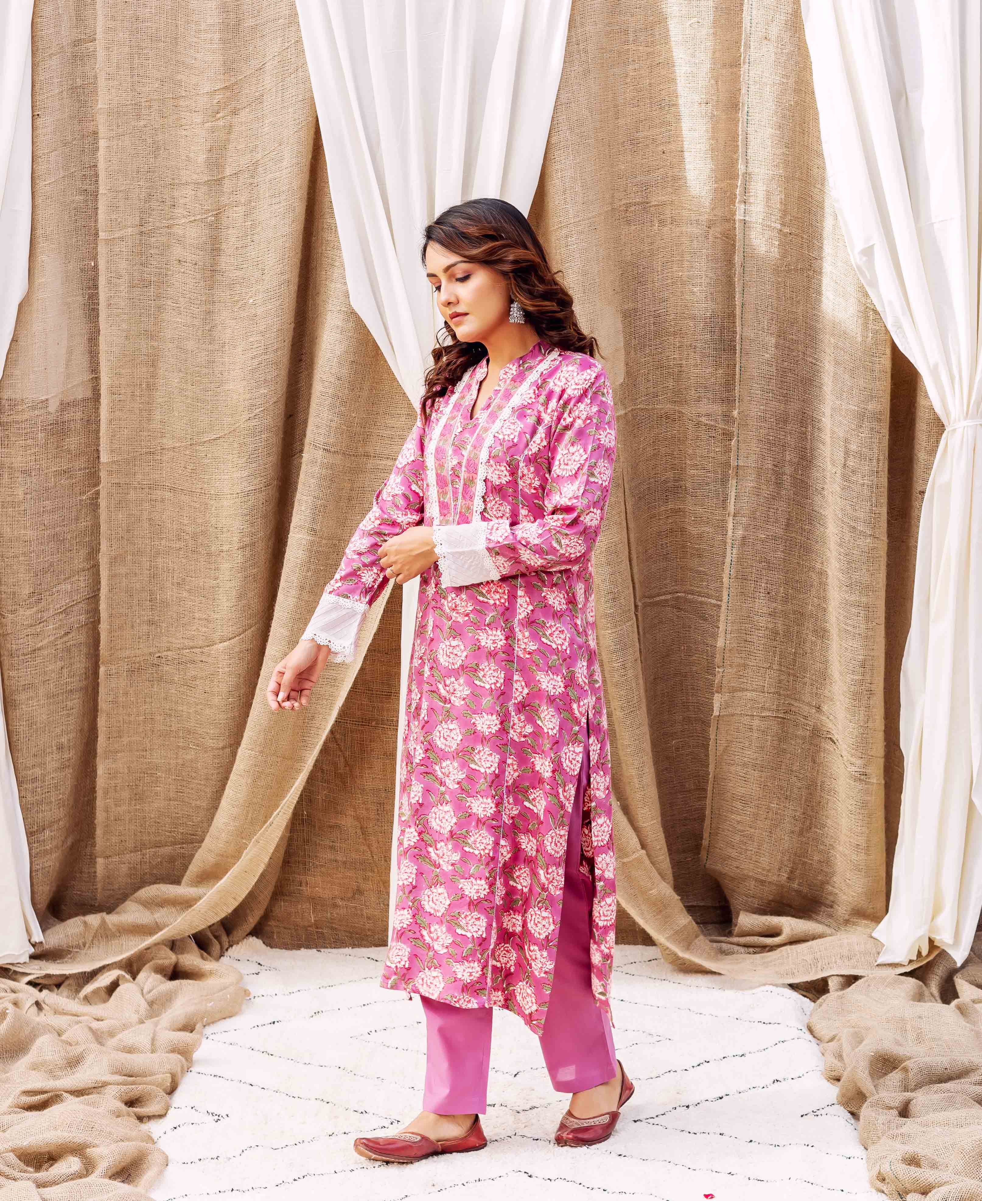 Model wearing a pink hand-block-printed floral kurta with white lace and matching pants.