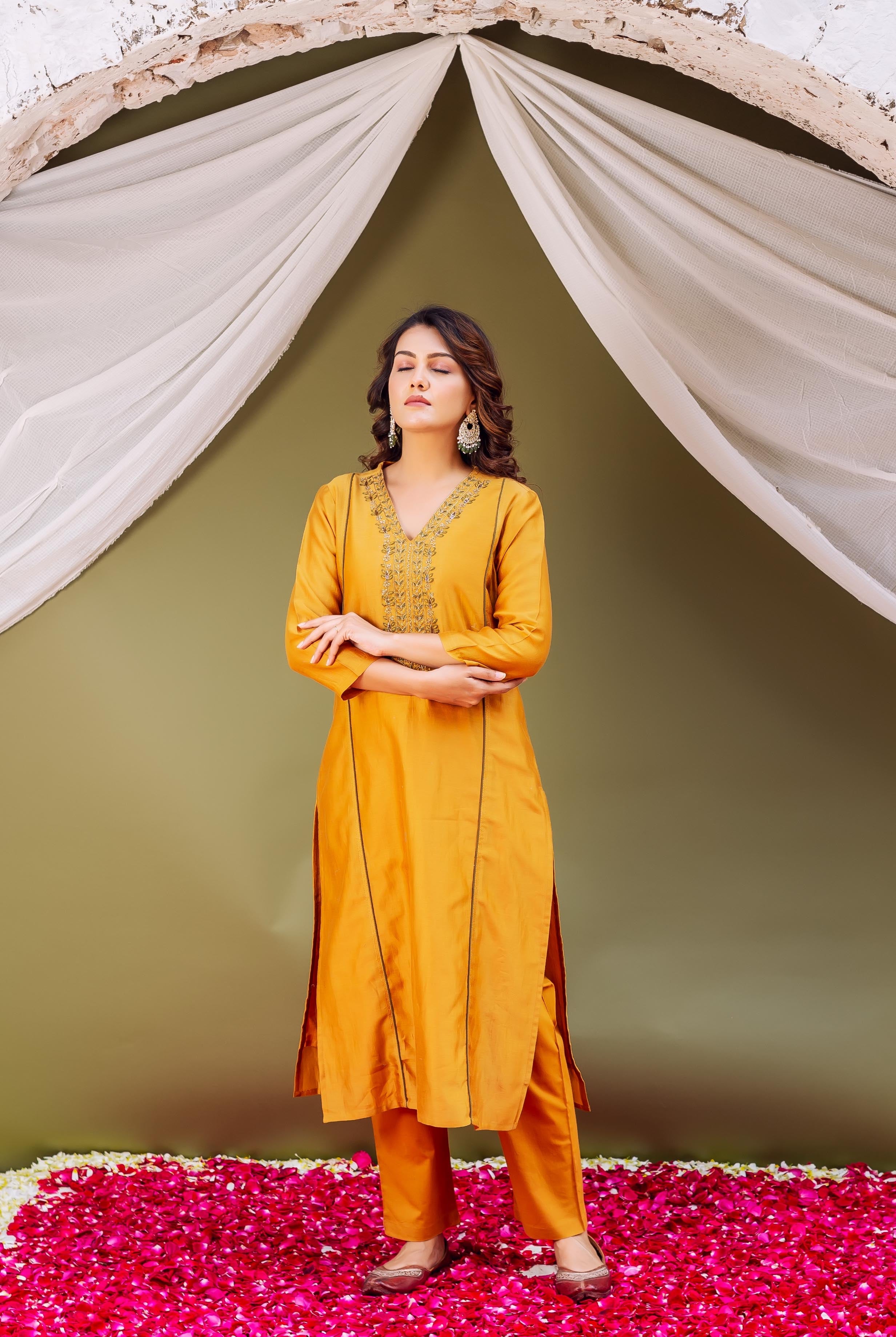 Full-body shot of model in mustard yellow kurta with intricate embroidered V-neck.