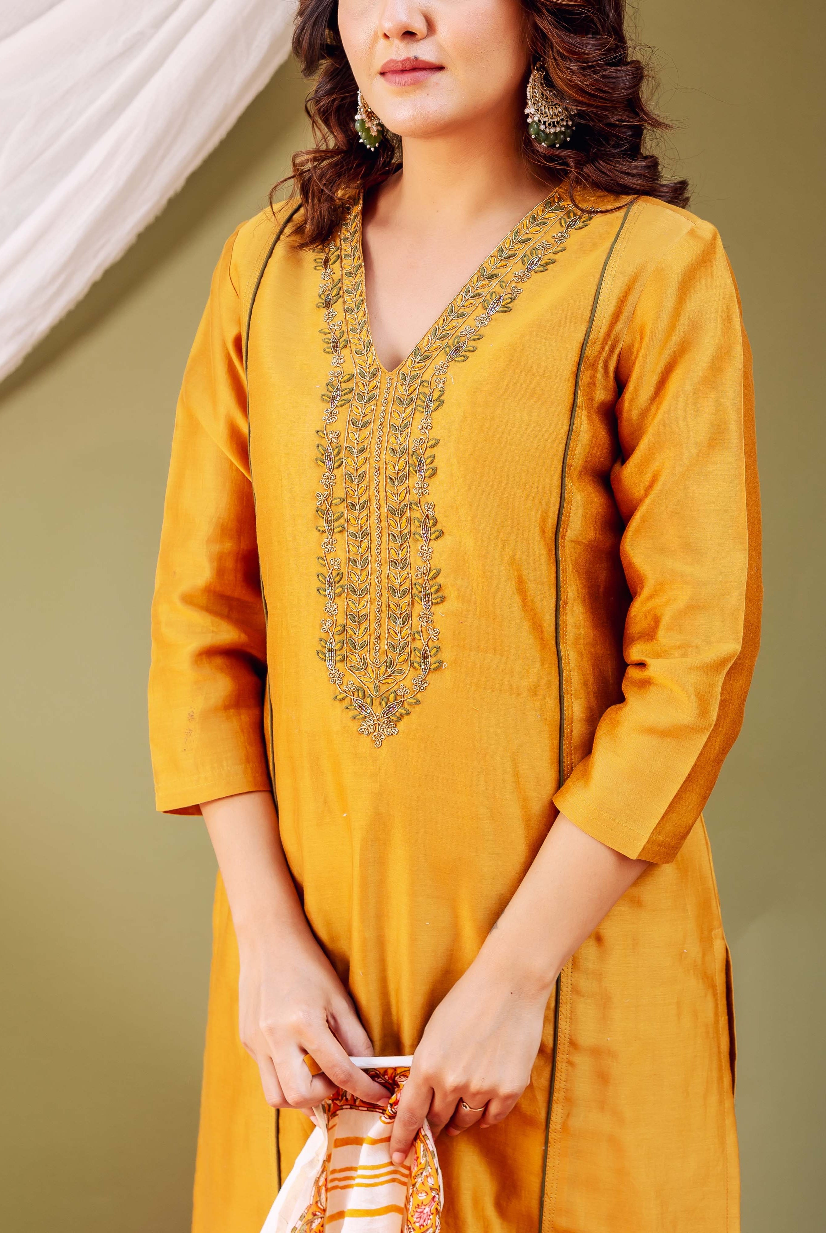 Mid-shot of model wearing a mustard silk Chanderi kurta with intricate embroidered V-neck.