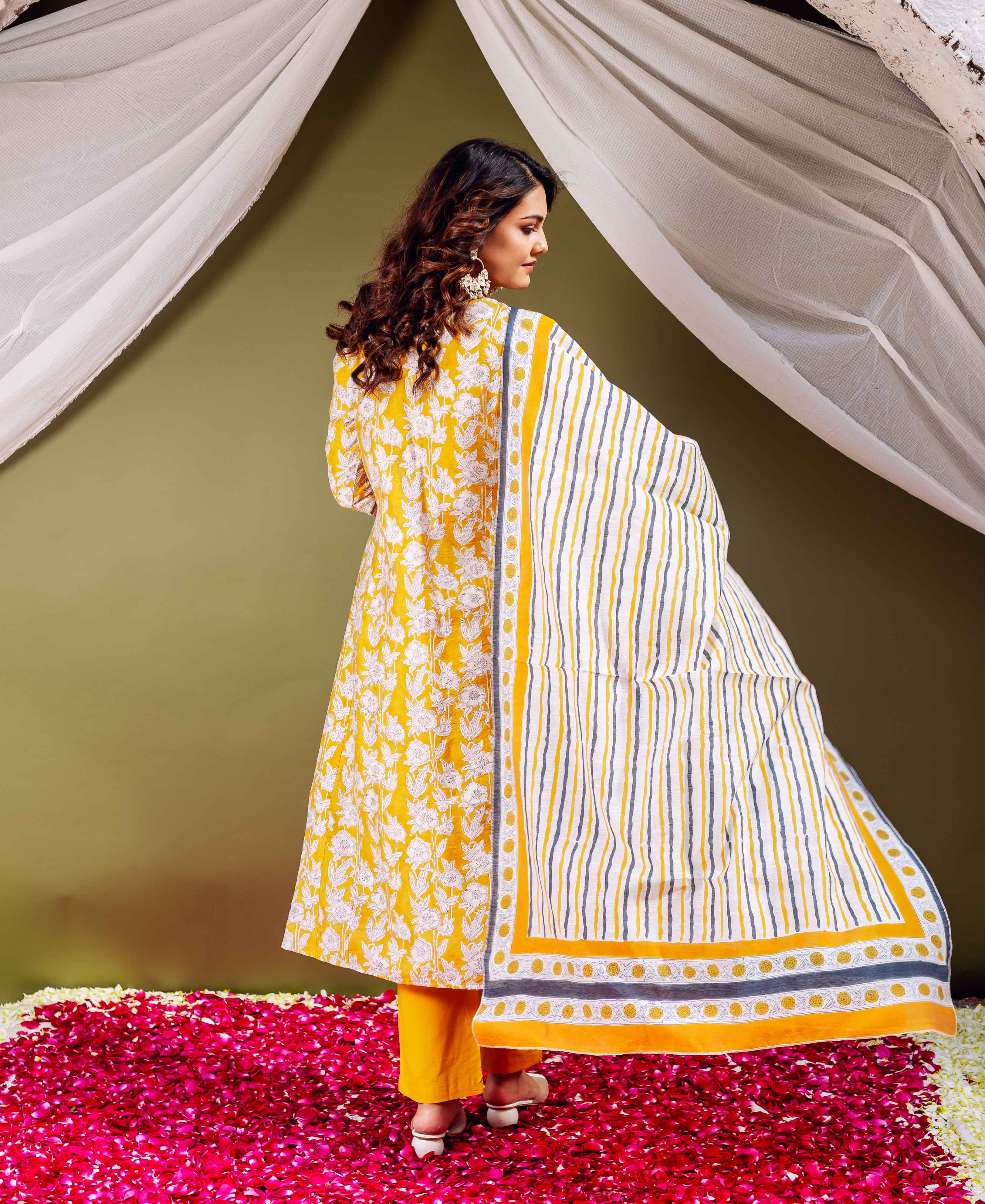 Model from behind, wearing yellow floral kurta and a flowing striped and geometric bordered dupatta.