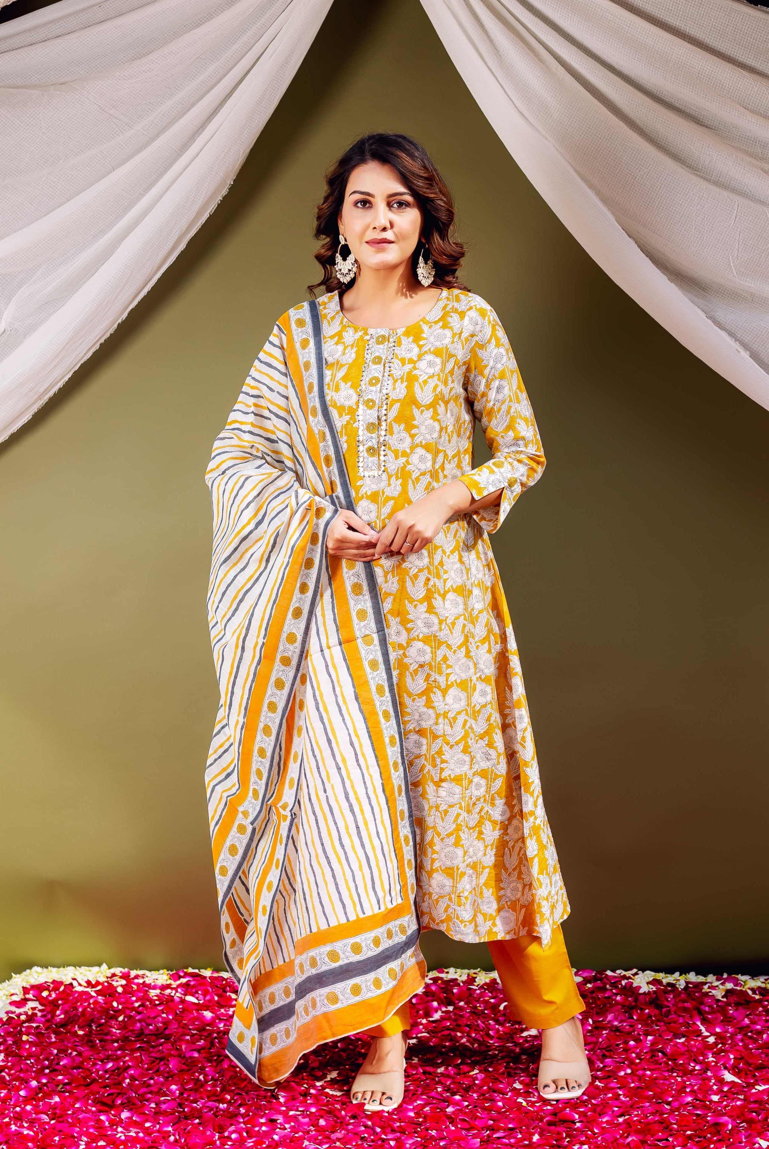 Woman in full-length mustard yellow floral block print kurta set with striped dupatta.
