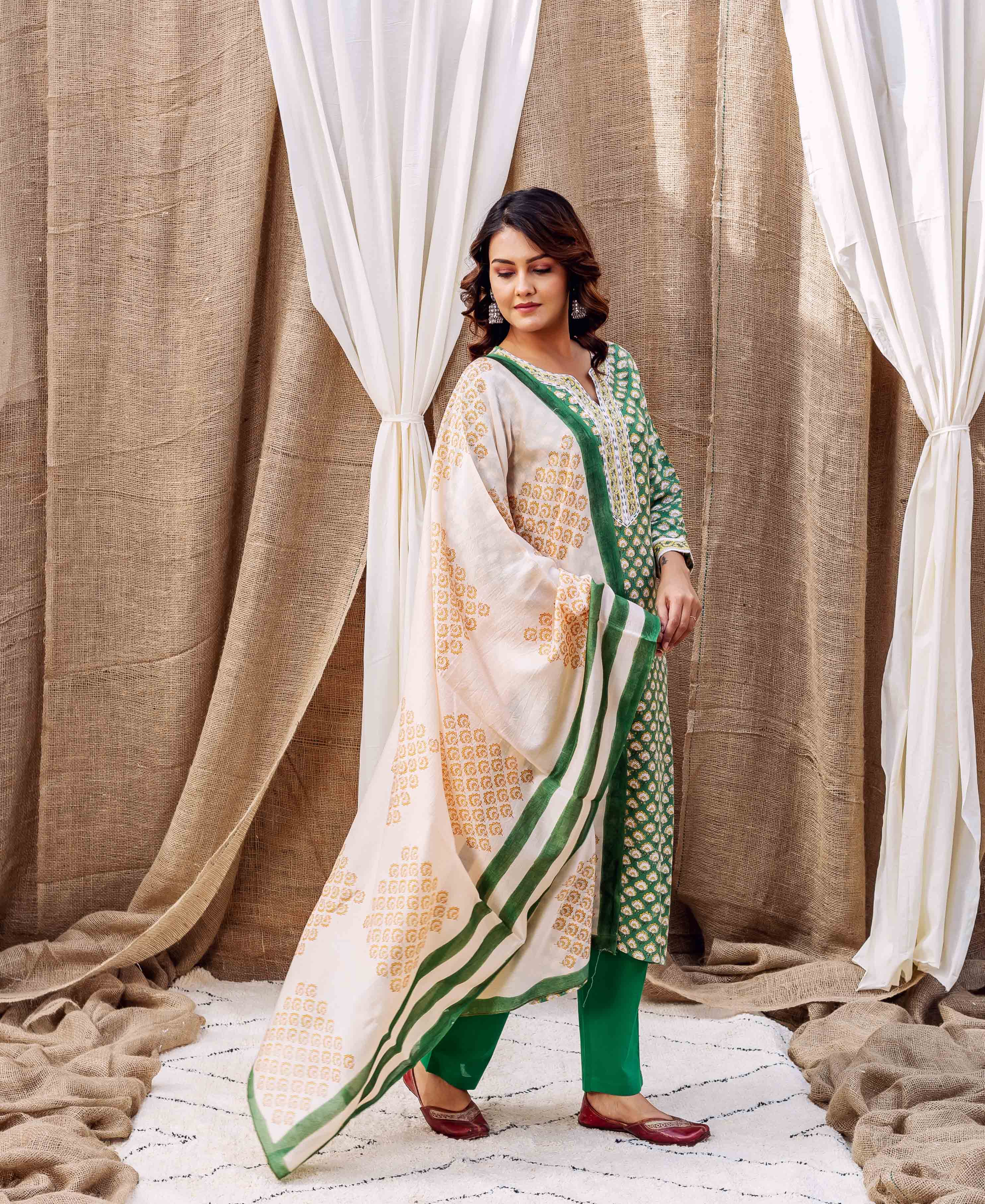 Model wearing cream dupatta with orange booti print and emerald green striped border.