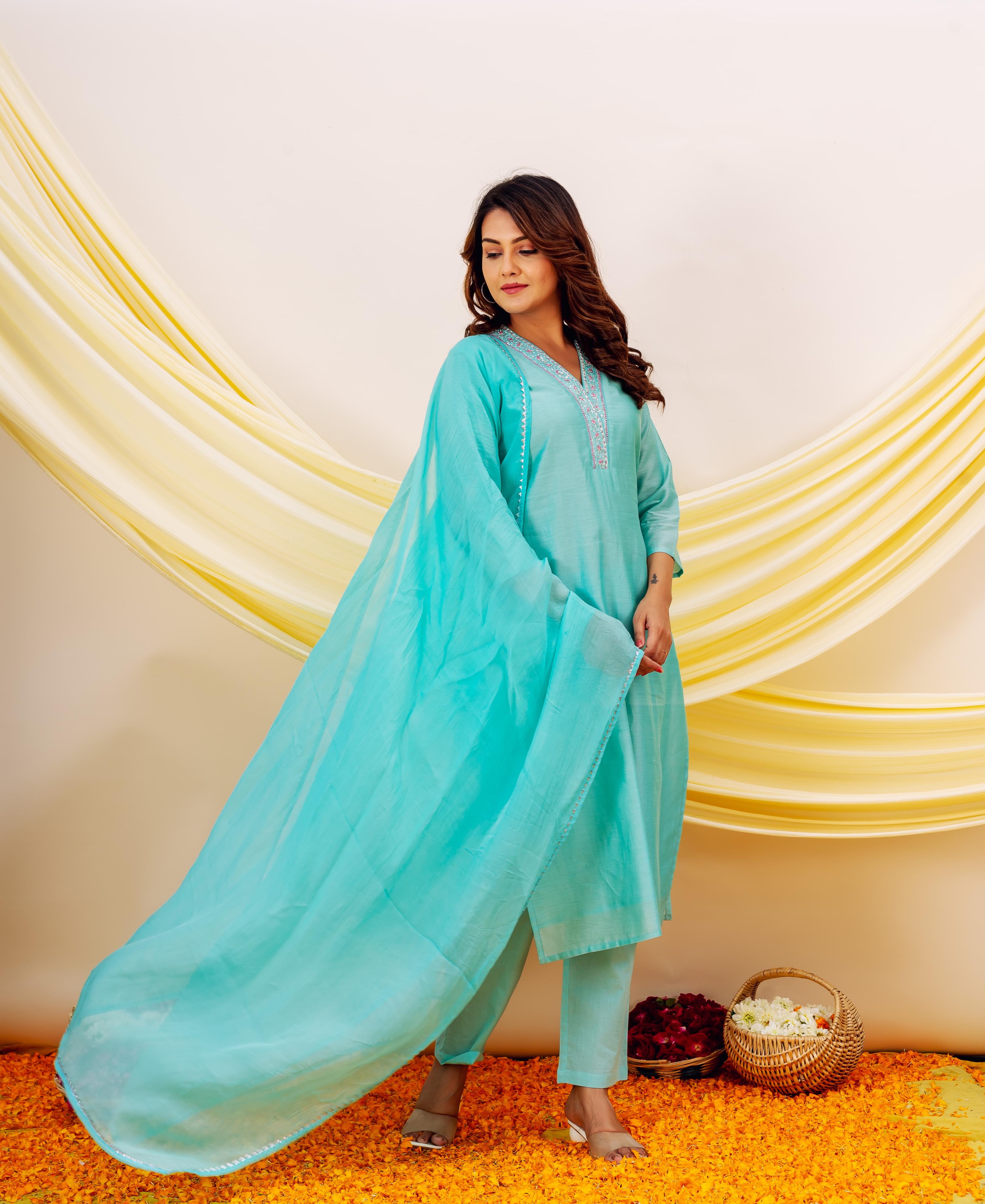 Turquoise outfit with embroidered neckline, flowing aqua organza dupatta with yellow and white drapes.