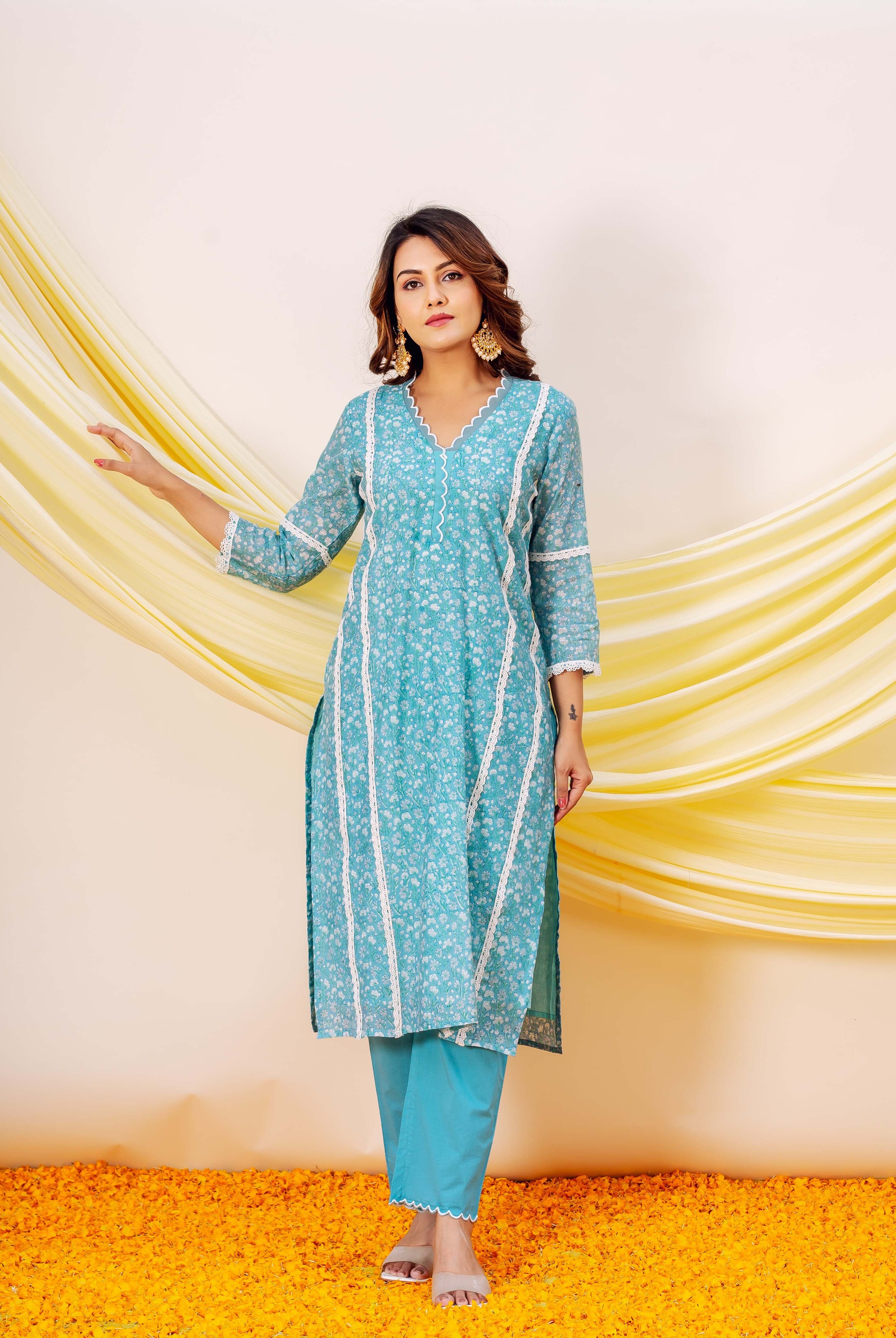 Front view of model wearing a turquoise blue hand-block printed kurta set with white lace trim.