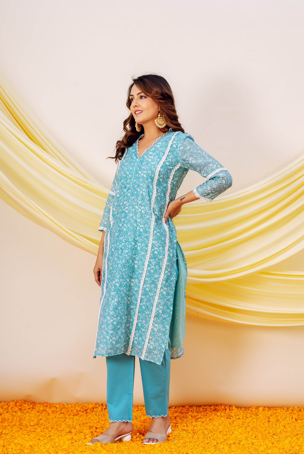 Model wears blue floral hand-block printed kurta and matching scalloped pants with white lace.