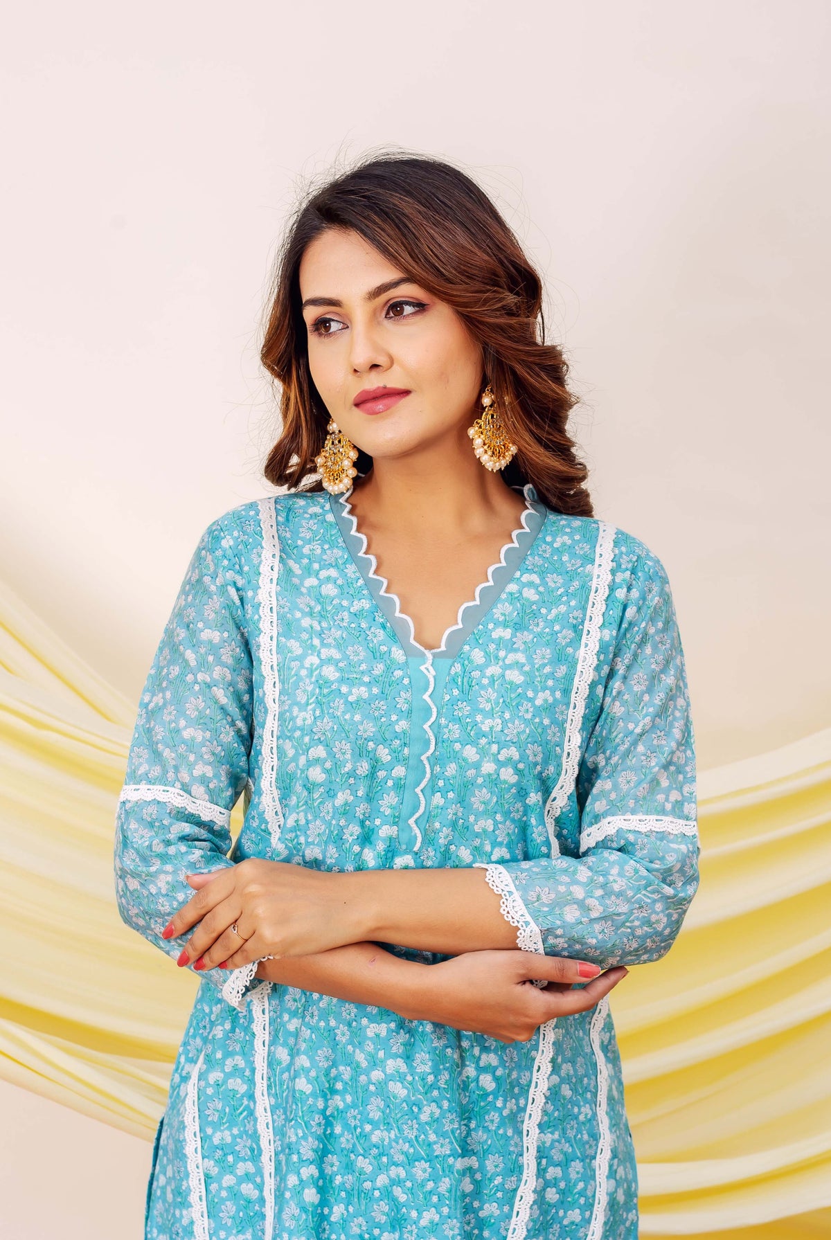 Front view of model wearing blue hand-block printed floral kurta with scalloped neckline and lace.