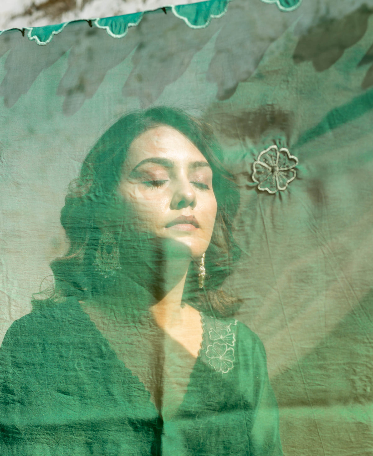 Model in regal forest green ensemble with embroidered sheer overlay.