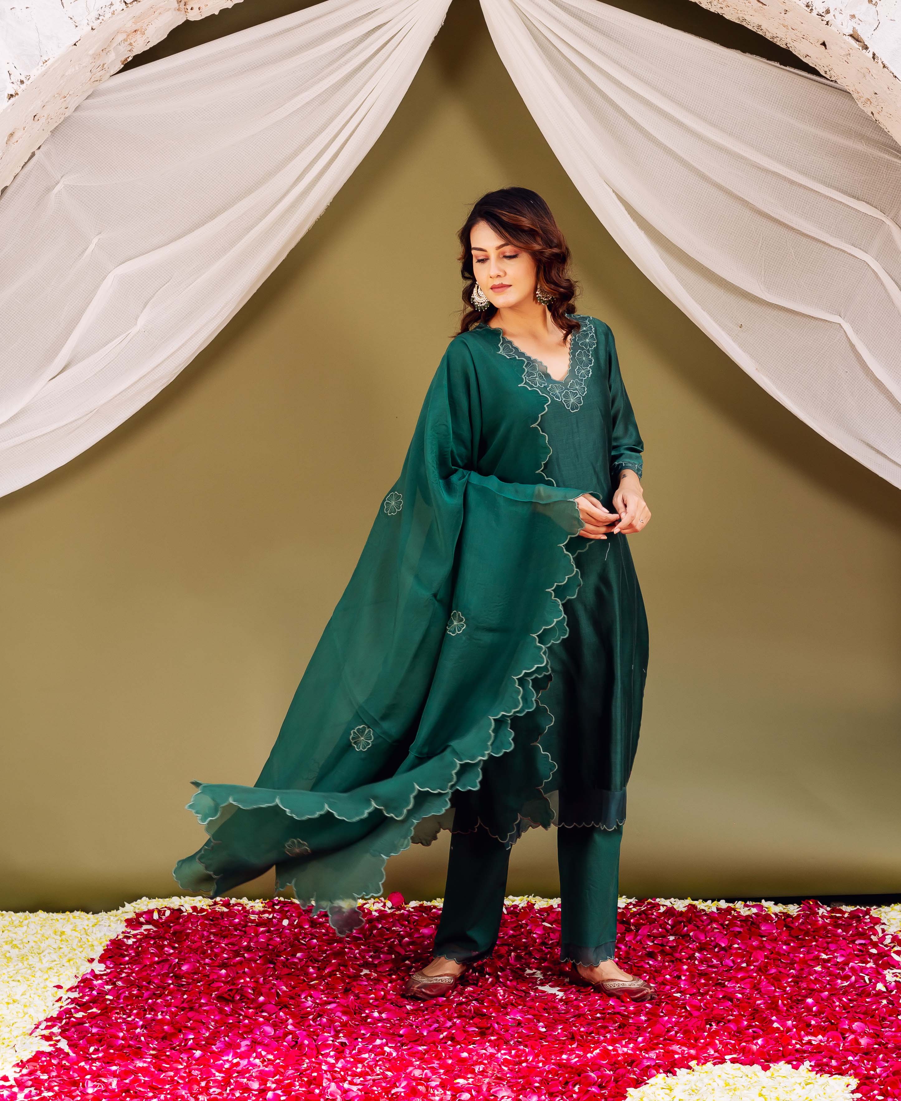 Model in a regal forest green silk ensemble, featuring white scalloped edges and floral motifs.