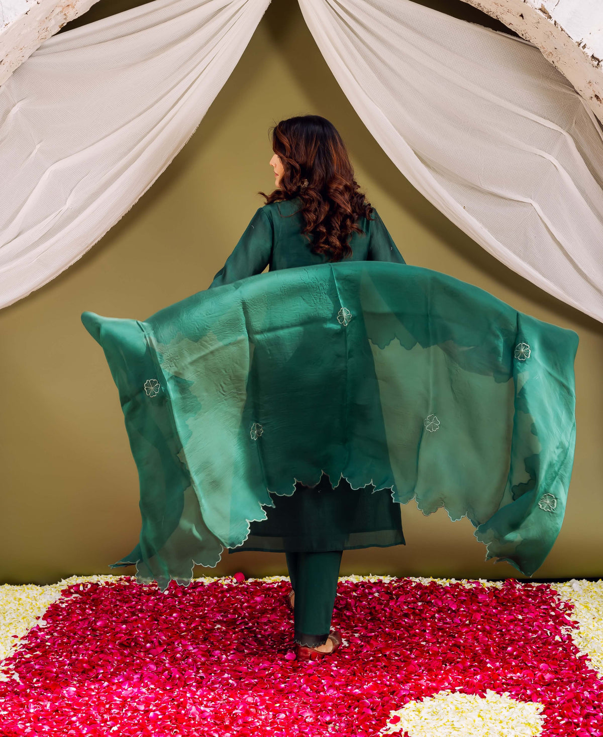 Rear view: woman in forest green ensemble, holding sheer scalloped block-printed dupatta.