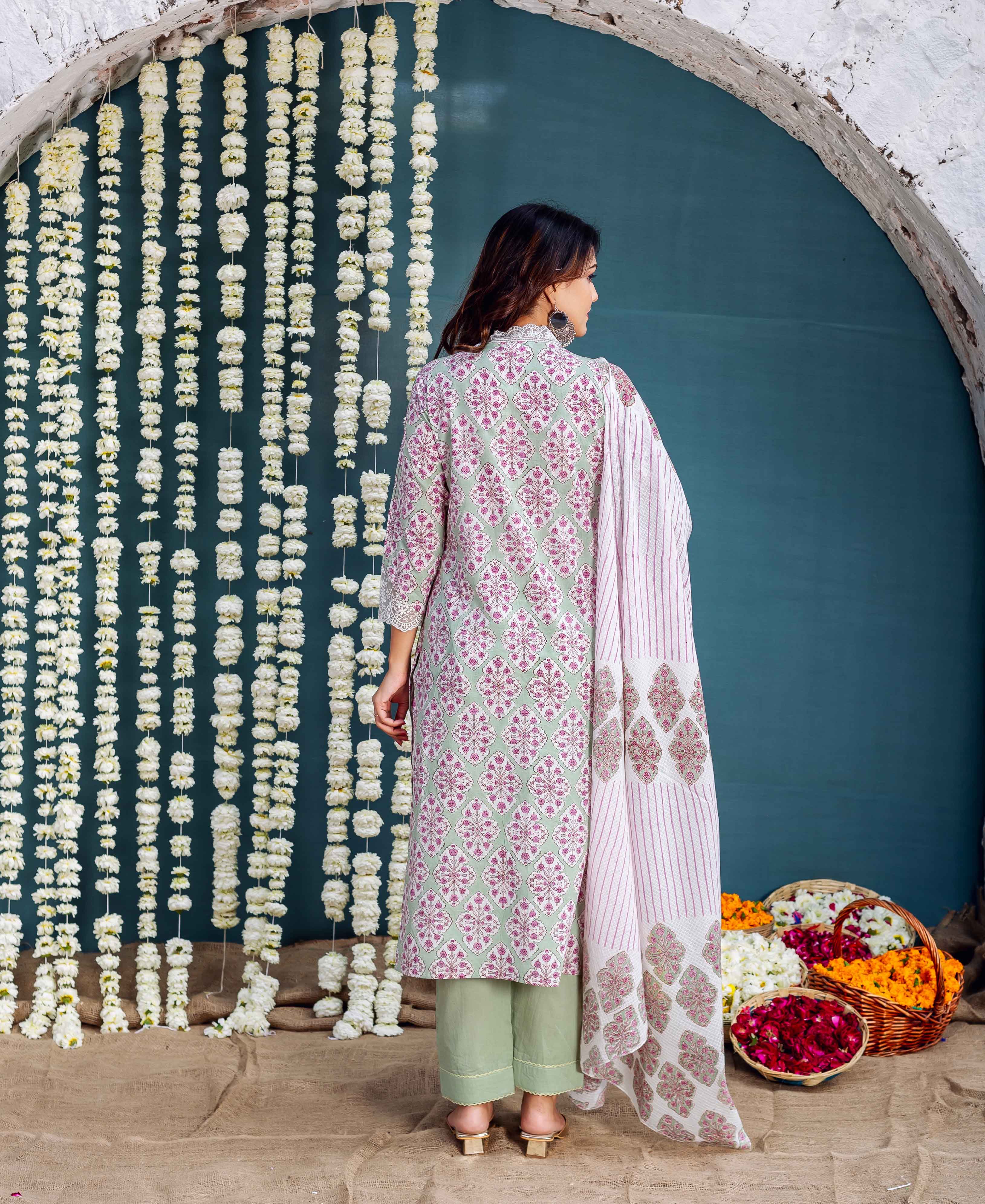 Model's back in sage green hand block printed kurta with geometric pink pattern.