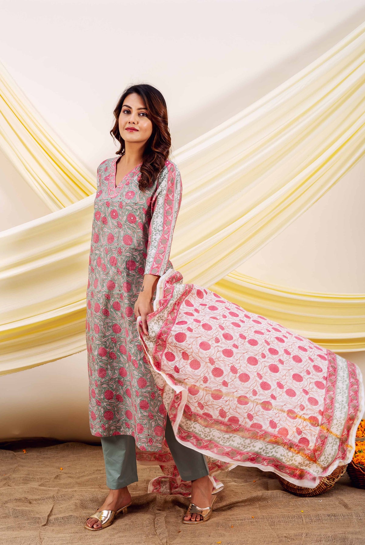 Full shot of a model wearing a grey and pink floral block printed kurta set with patterned dupatta.