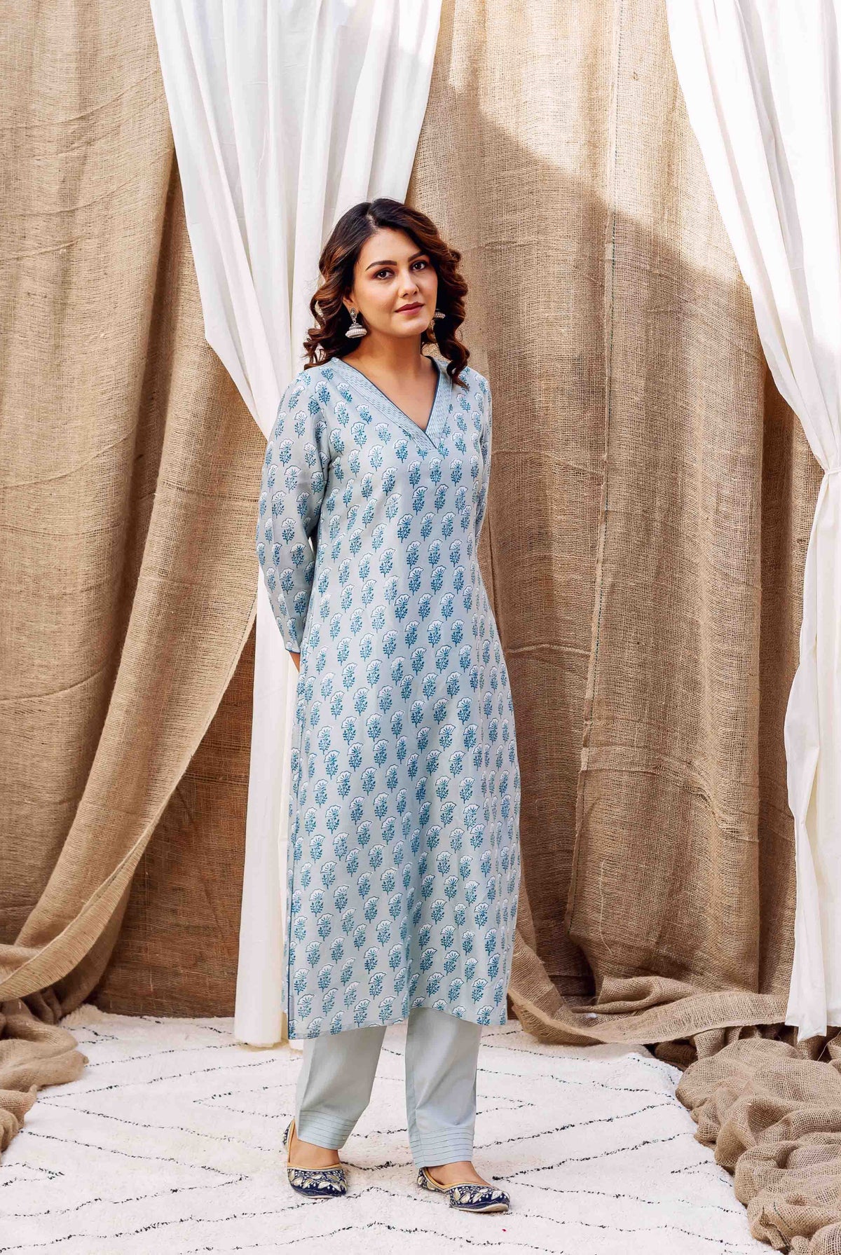 Woman in a slate hand-block-printed kurta featuring blue leaf motifs and matching pants.