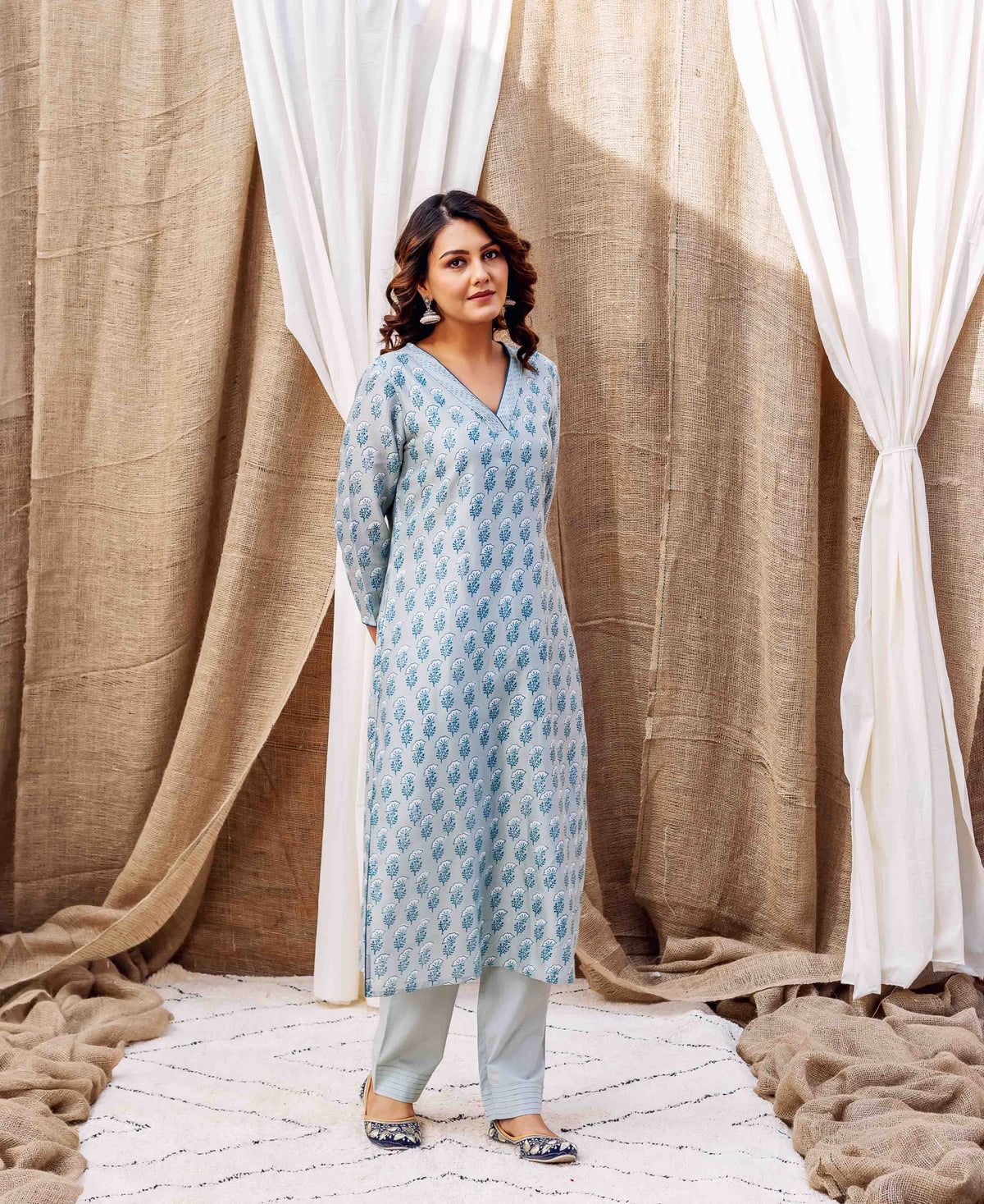 Woman in a slate hand-block-printed kurta featuring blue leaf motifs and matching pants.