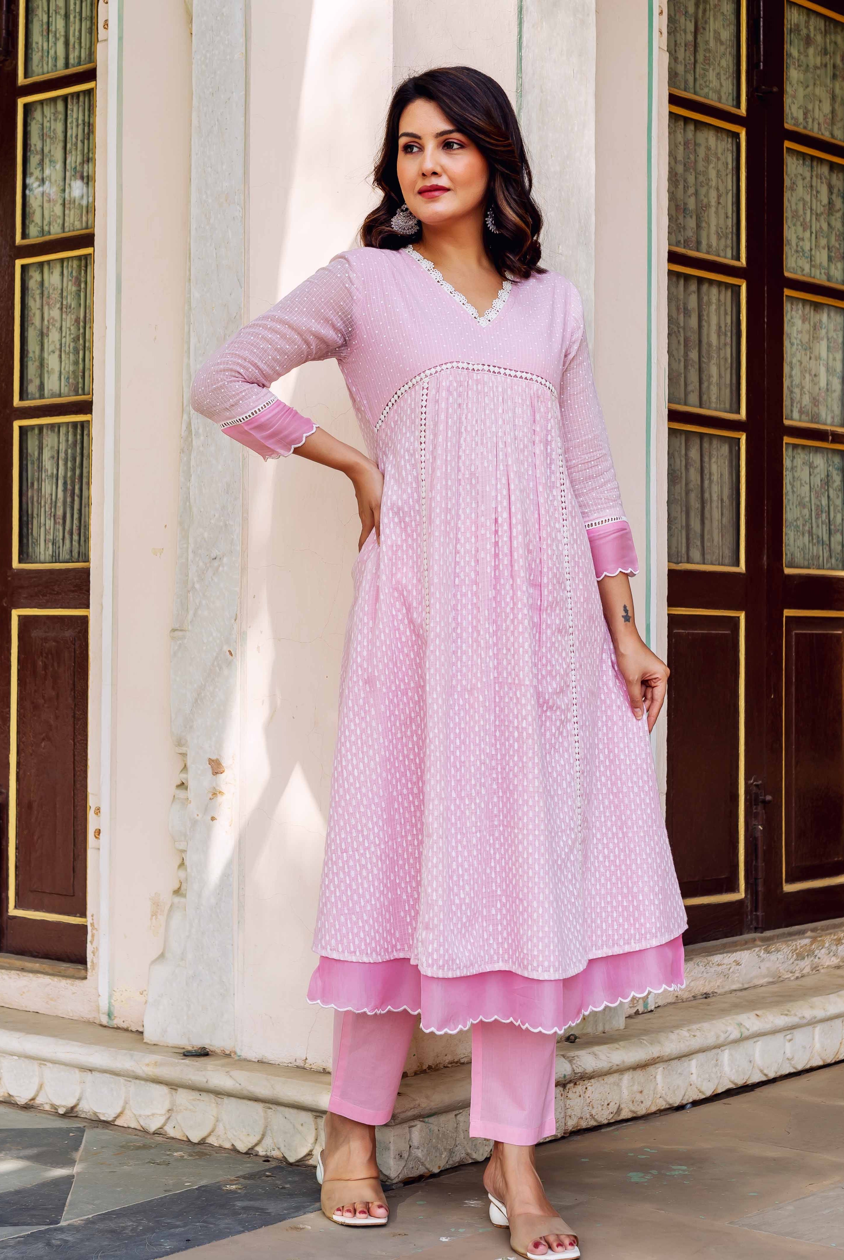 Full front view of woman wearing a pink block-printed layered kurta and matching trousers.