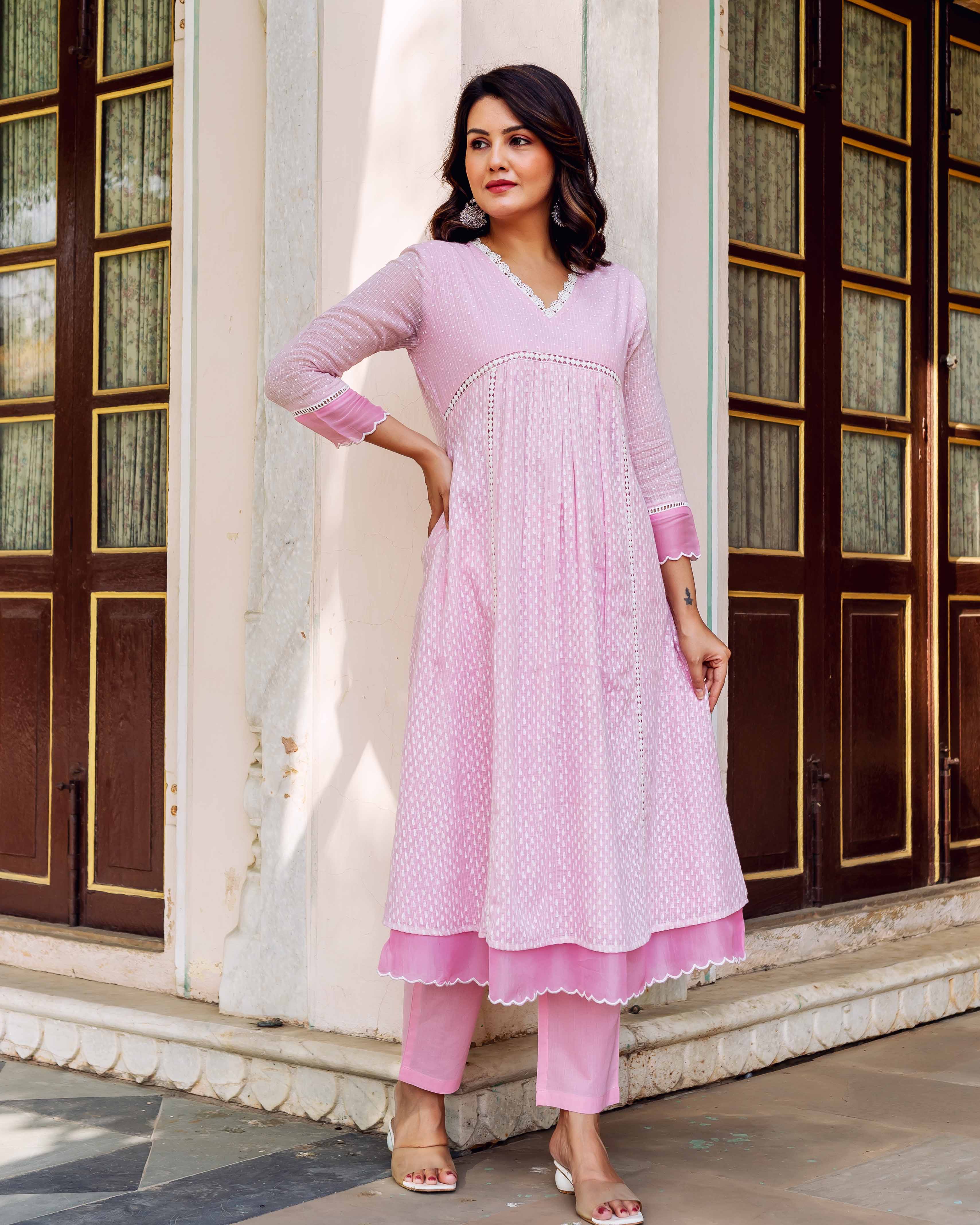 Full front view of woman wearing a pink block-printed layered kurta and matching trousers.