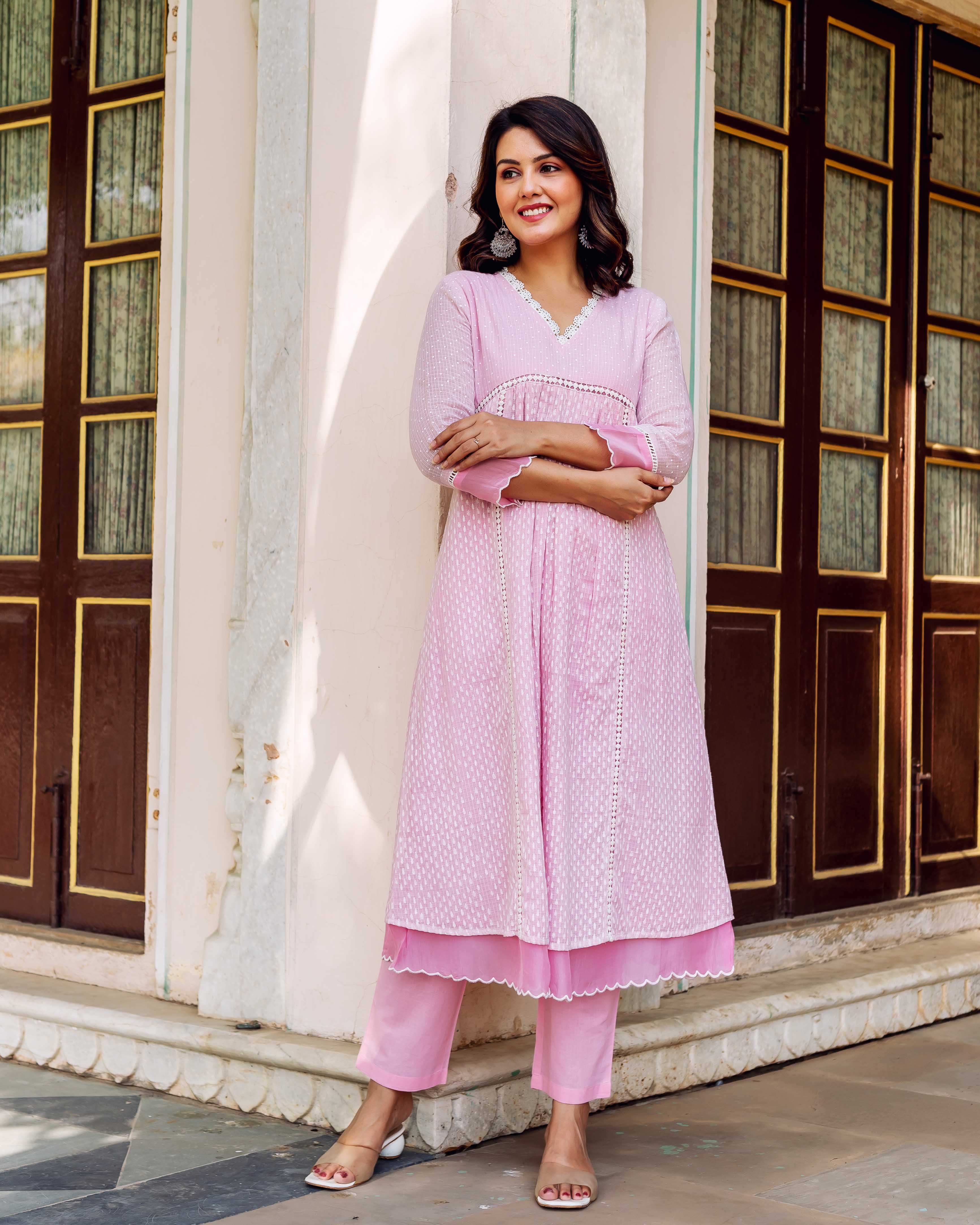 A model wearing a pink, white-printed kurta with lace trim and matching pants.