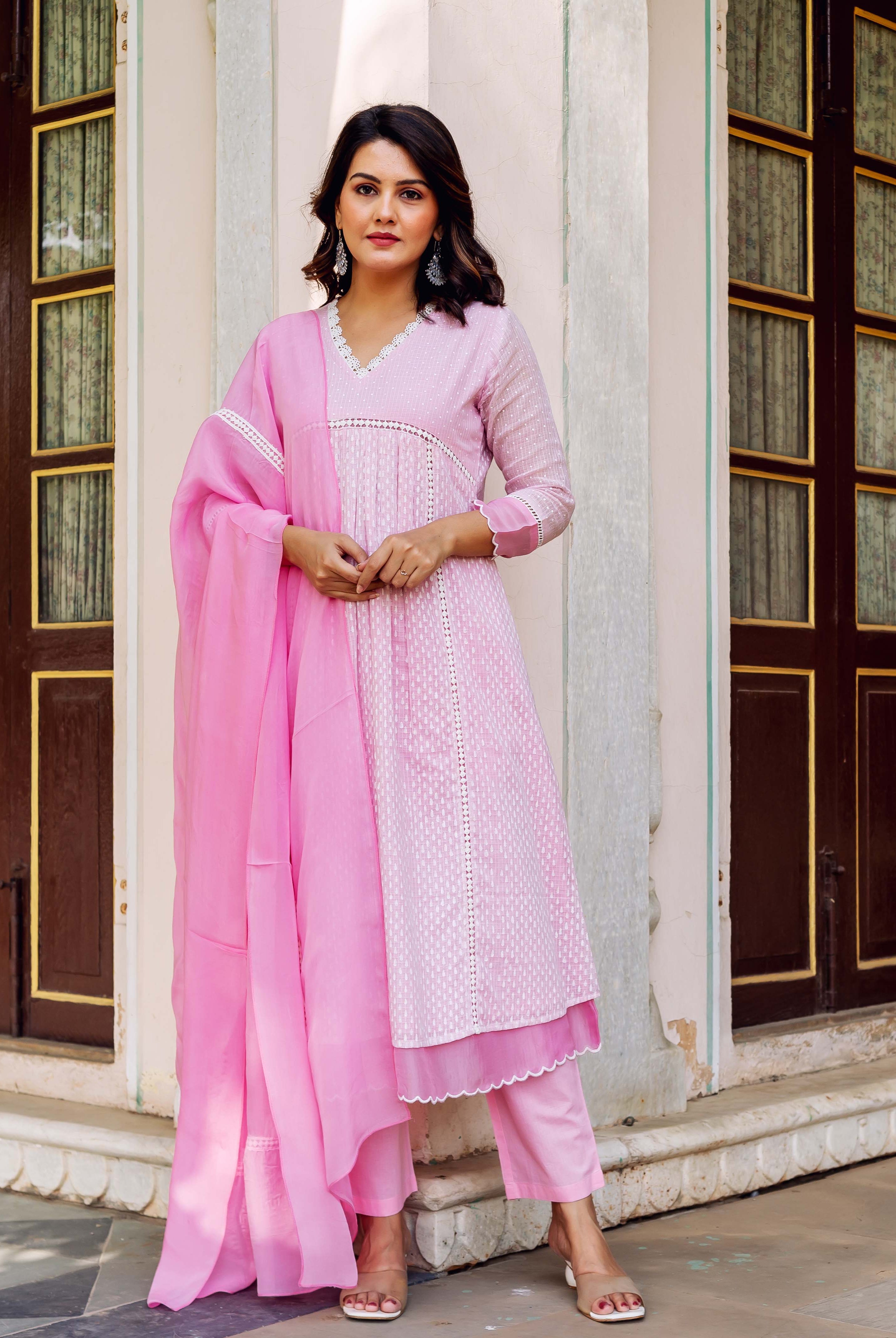 Front view of a model in a pink hand-block printed kurta set with white patterns and lace.