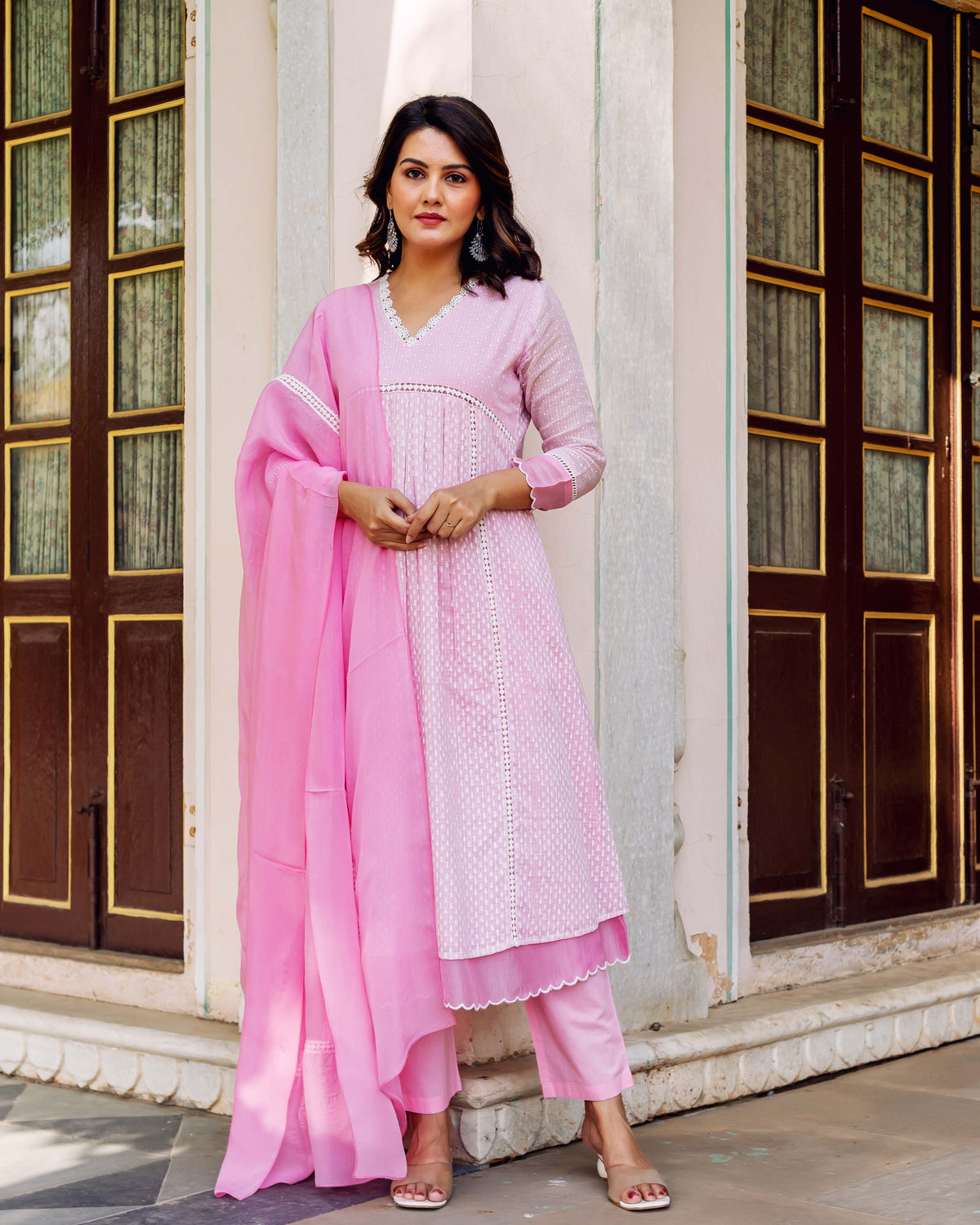 Front view of a model in a pink hand-block printed kurta set with white patterns and lace.