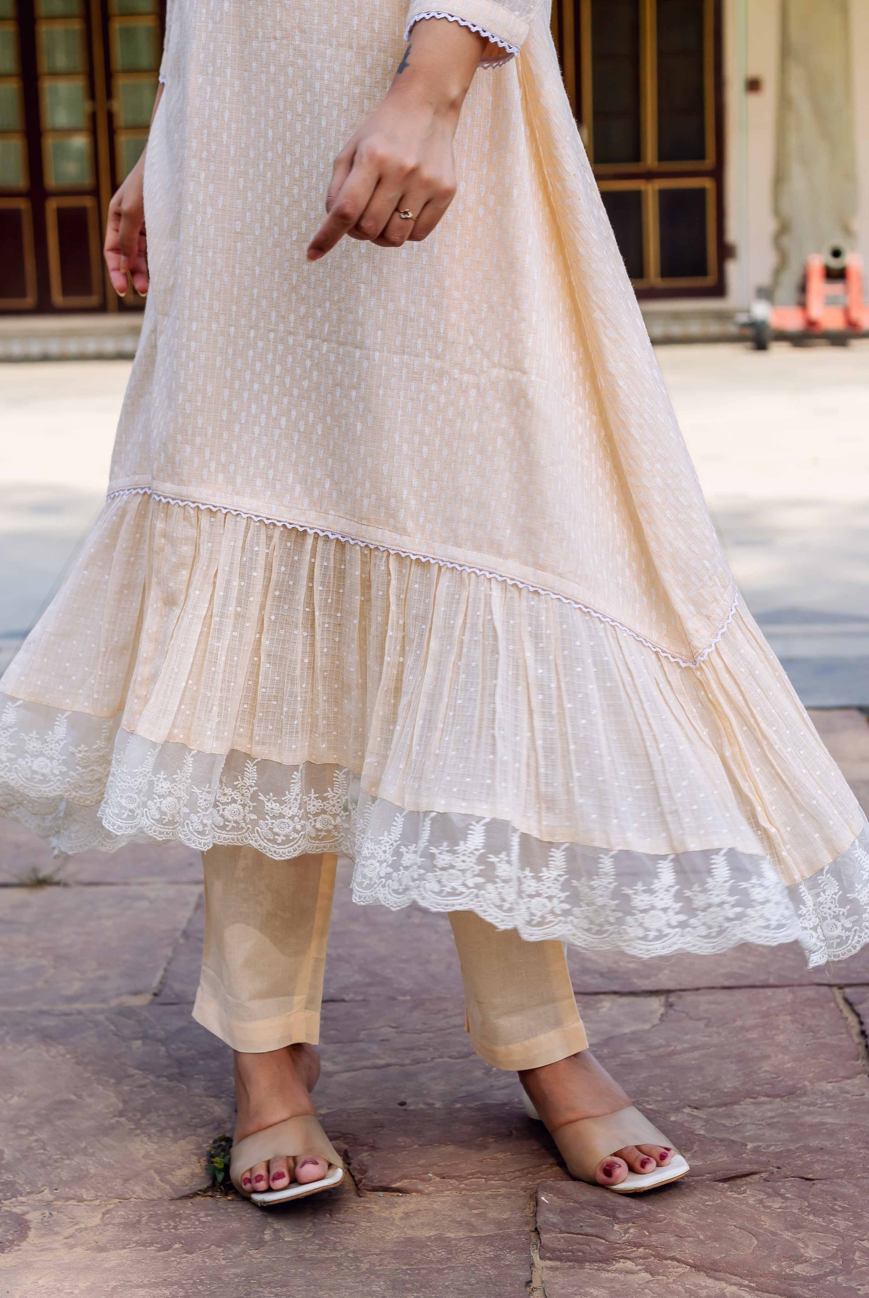 Model in light peach hand-block printed ethnic kurti with ruffled lace hem, matching pants.