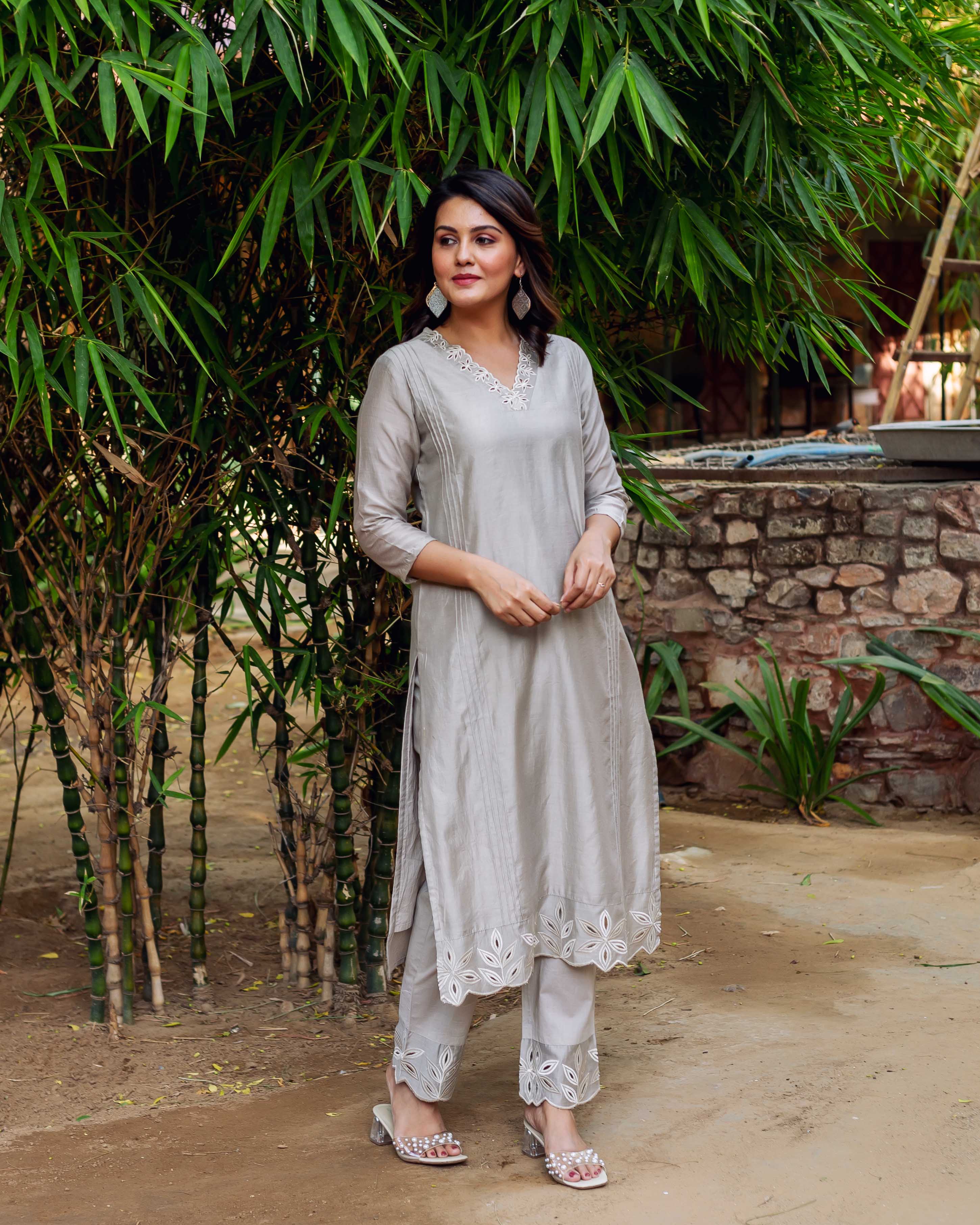 Woman in a silver-grey silky kurta set with white embroidered neck and cutwork hems.