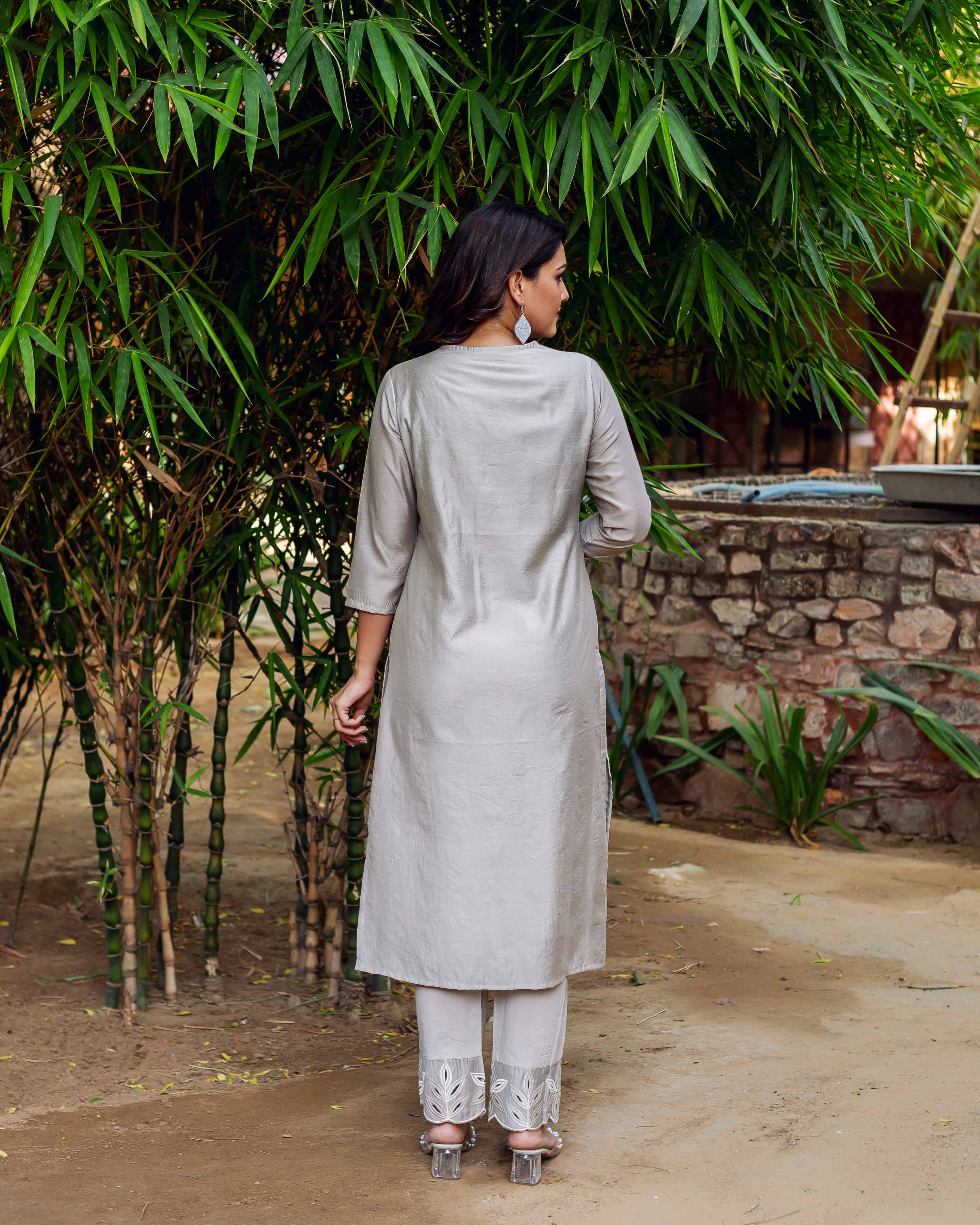 Back view of model in silver chanderi silk kurta with embroidered neckline and pants.
