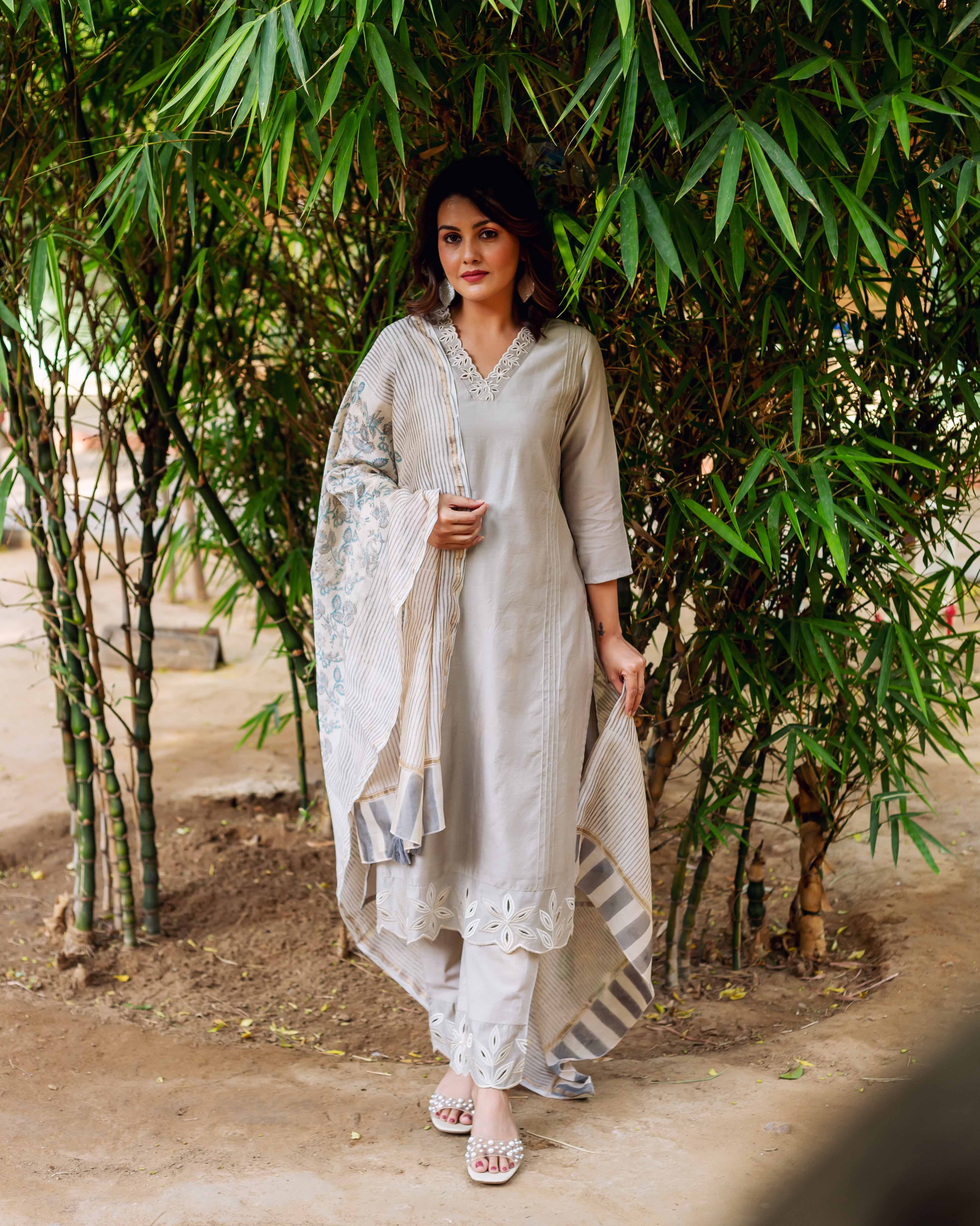 Full-length model in silver mist embroidered kurta set with floral cutouts and printed dupatta.