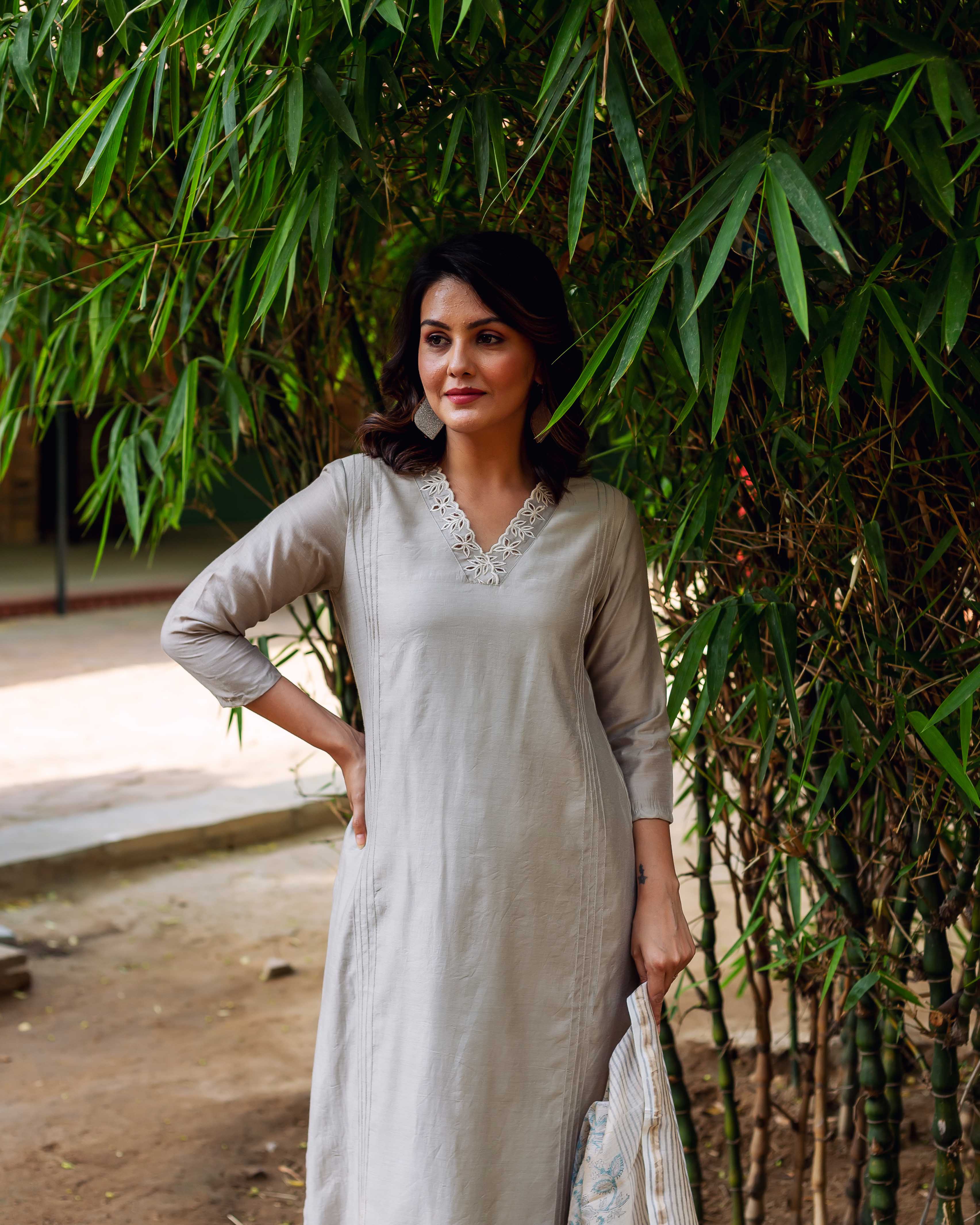 Model in a silver mist Chanderi silk kurta with intricate embroidered neckline, standing outside.