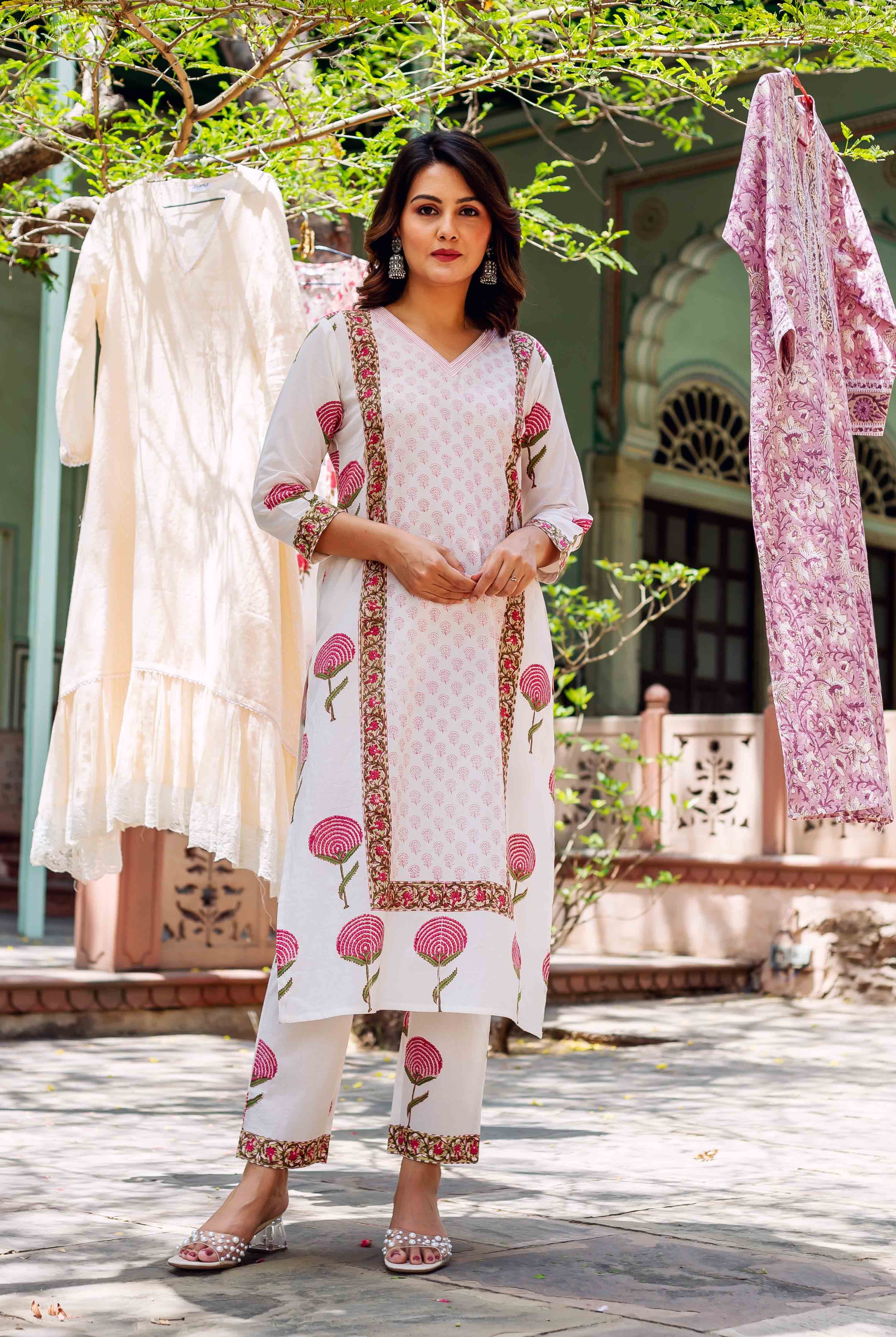 Full-length model in white hand-block printed cotton kurta set with vibrant pink floral motifs.