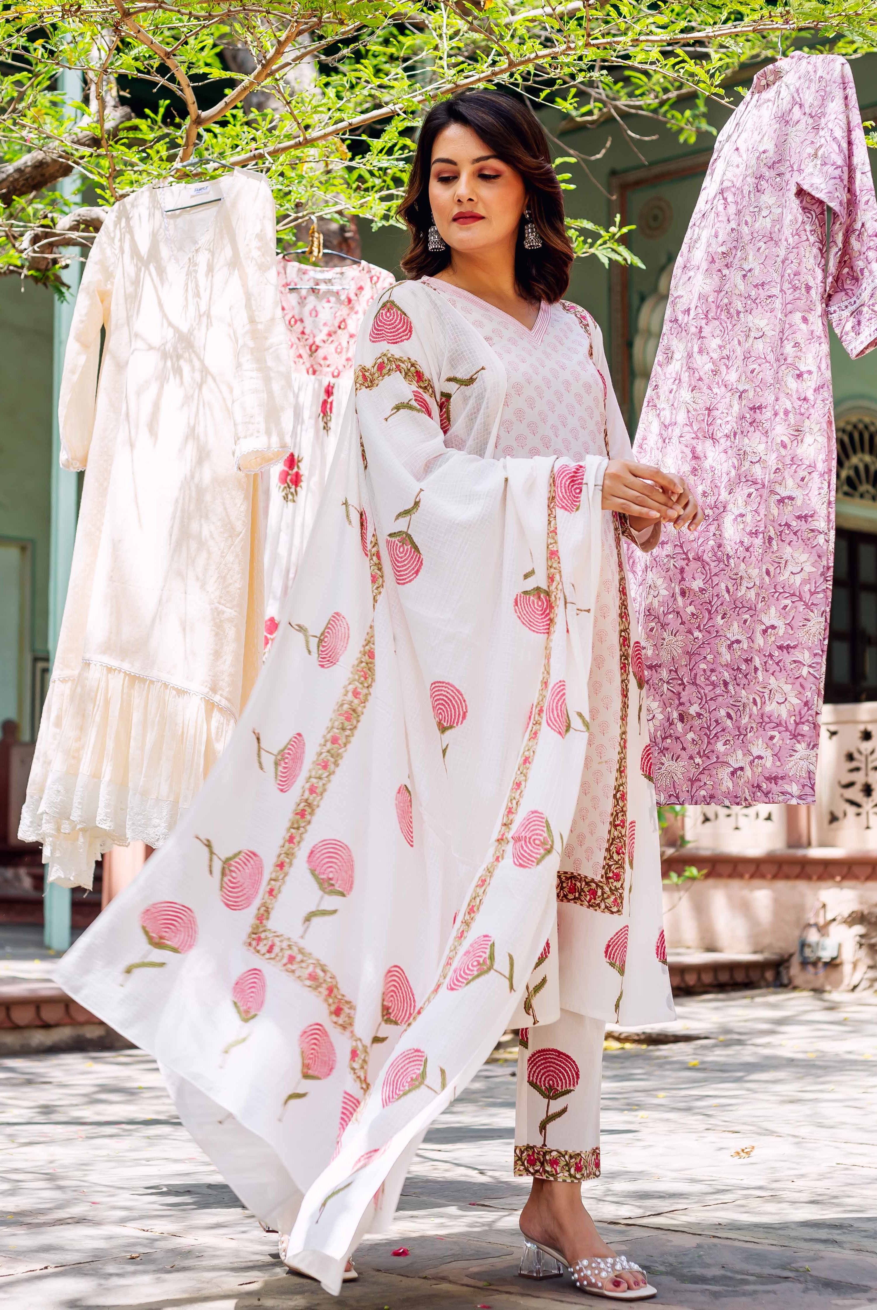 Woman in white hand-block-printed cotton kurta set with pink floral designs, flowing dupatta.