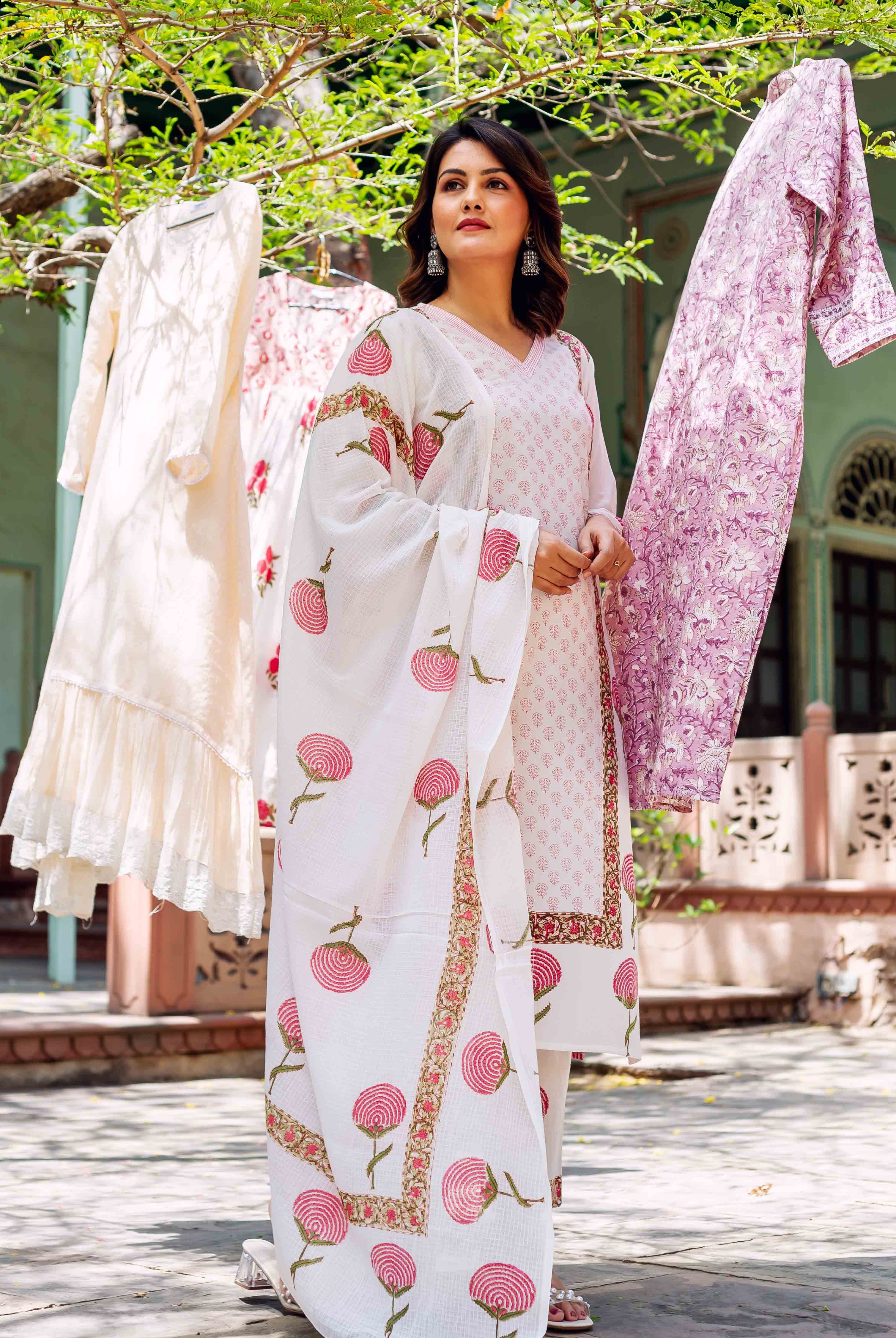 Woman in white hand-block printed cotton kurta set with pink stylized floral patterns.