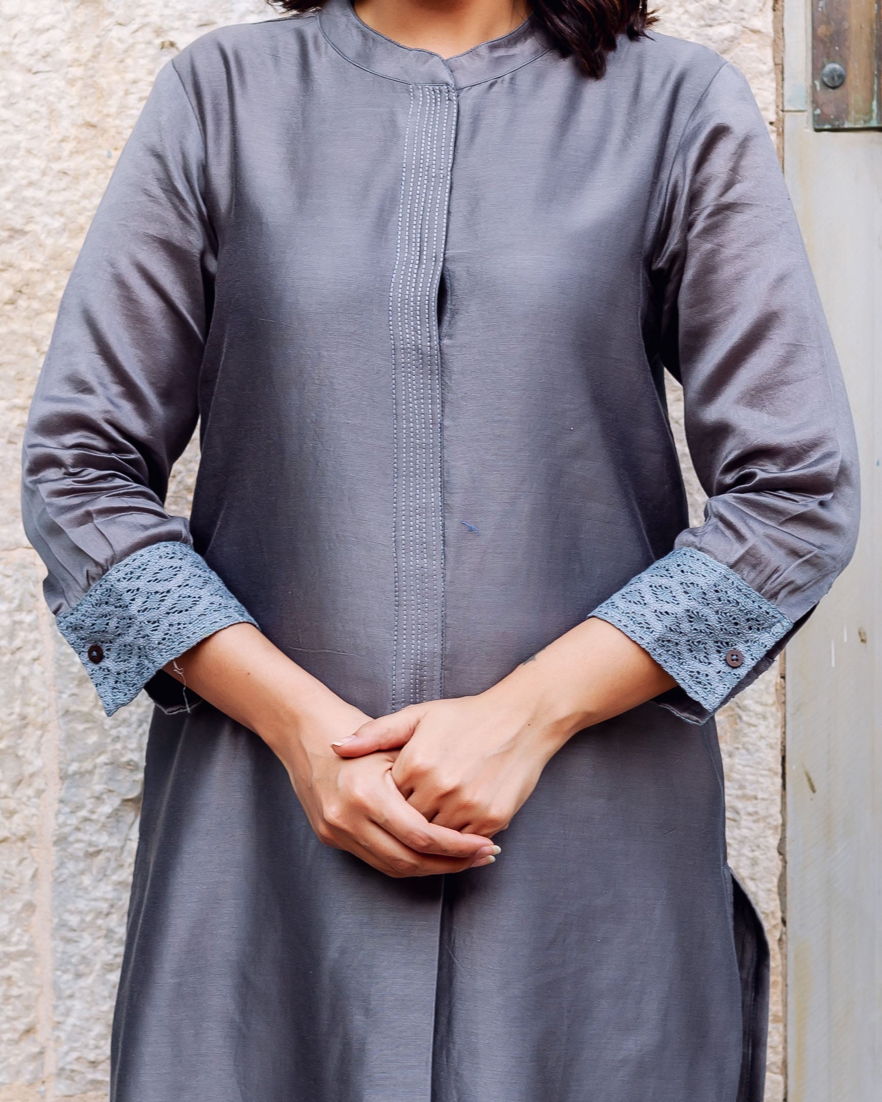 Model wearing grey chanderi silk kurta with embroidered placket and patterned blue cuffs.