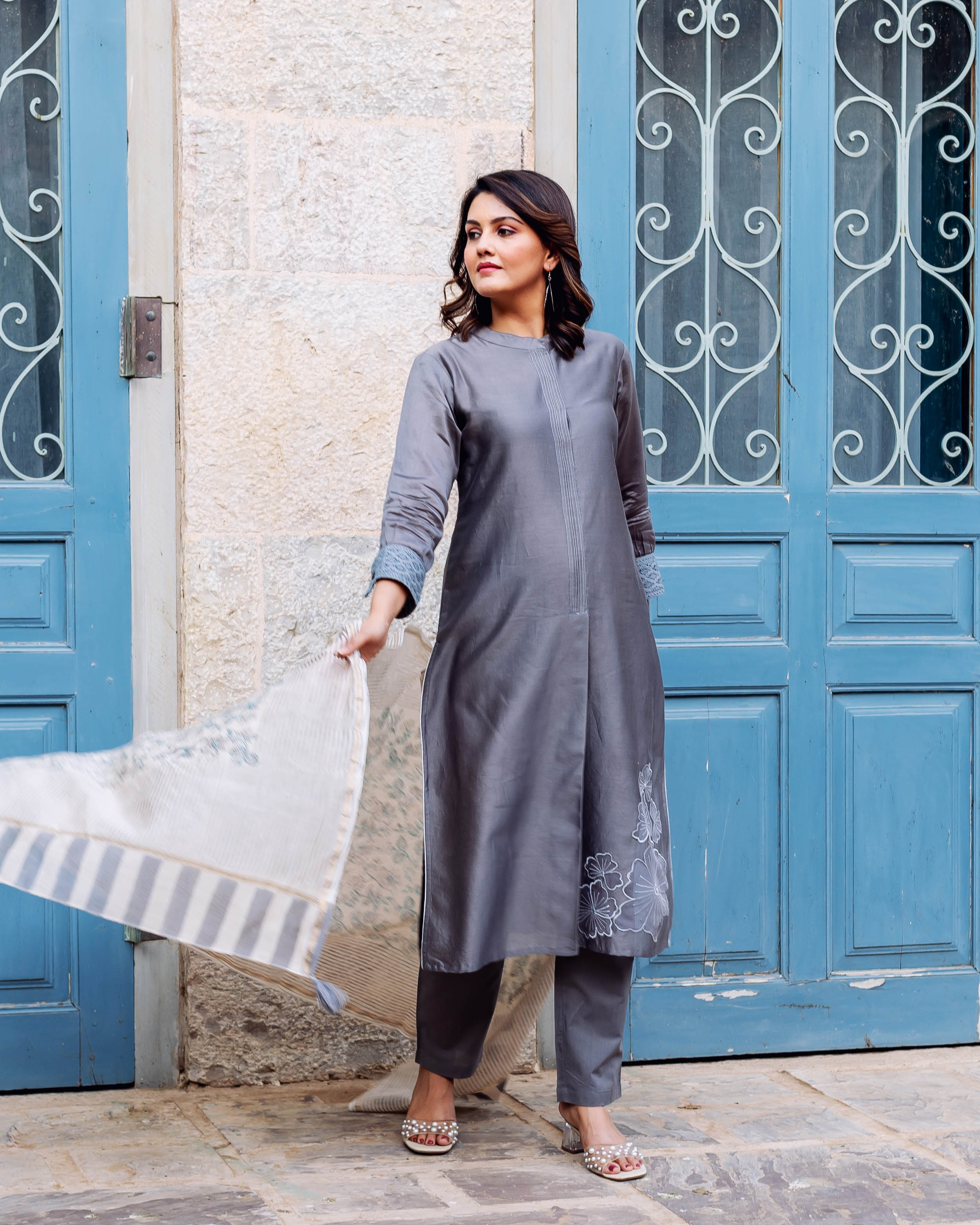 Model in a silver mist embroidered kurta set with pintucks and a patterned, flowy dupatta.