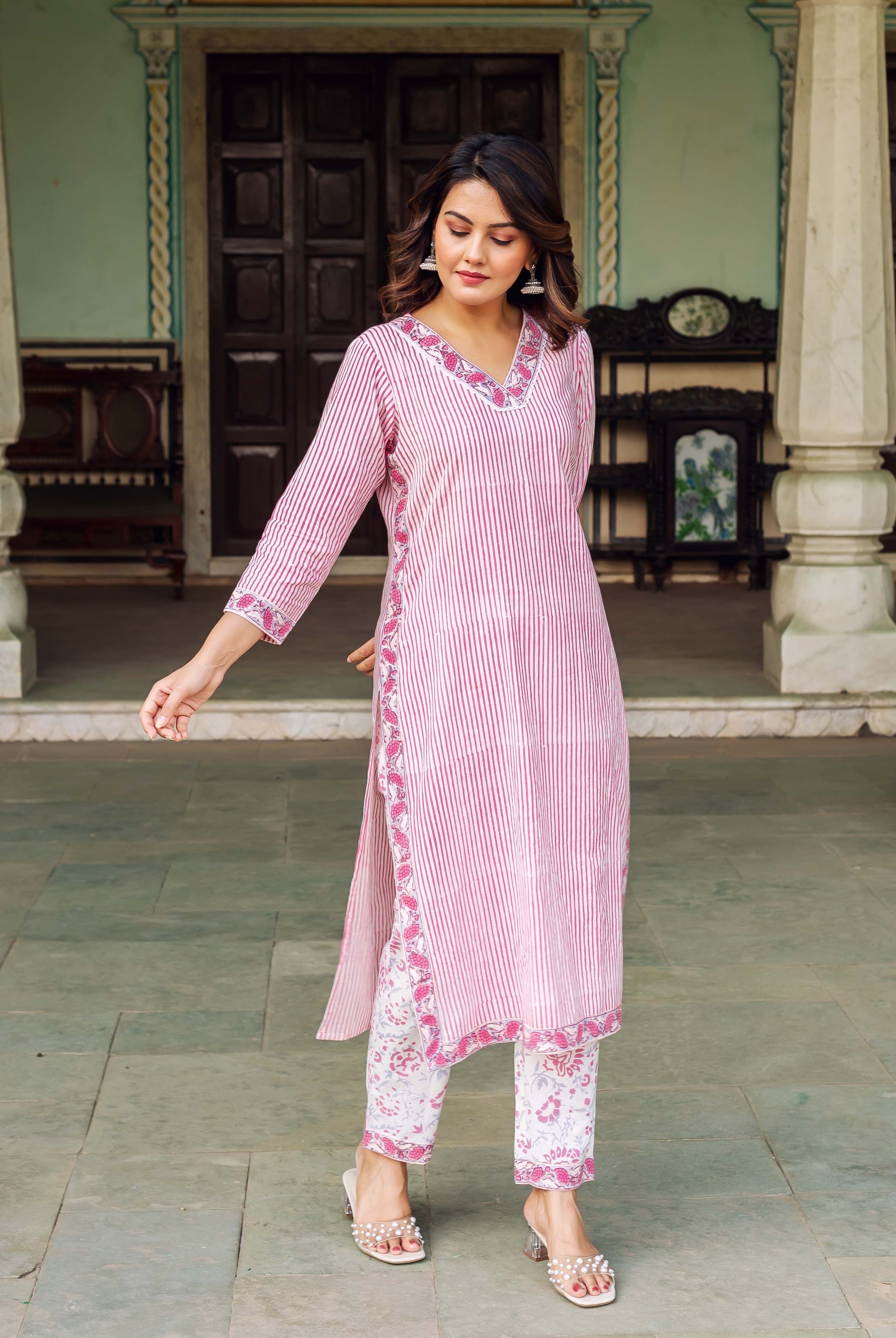 Woman in full-length white and pink striped kurta with floral trim and printed pants.