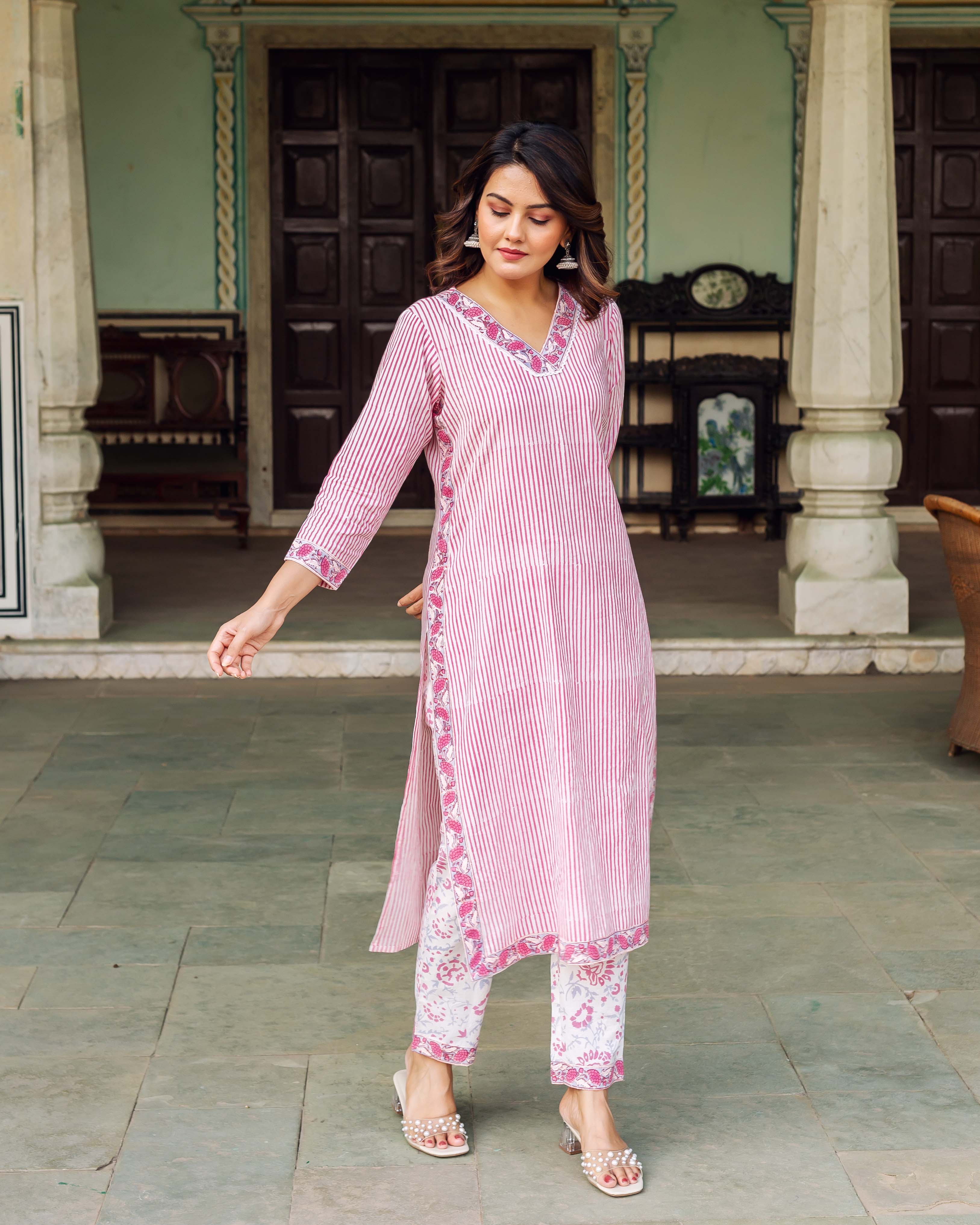 Woman in full-length white and pink striped kurta with floral trim and printed pants.