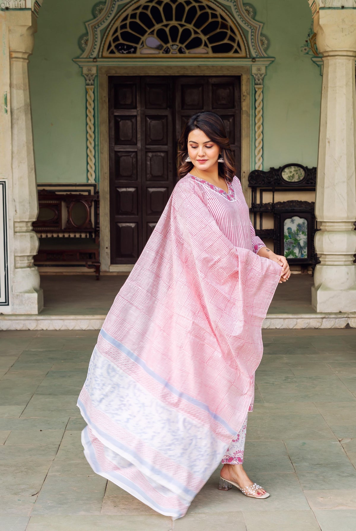 Woman wearing a white and pink striped hand-block-printed kurta with elegance and poise outdoors.
