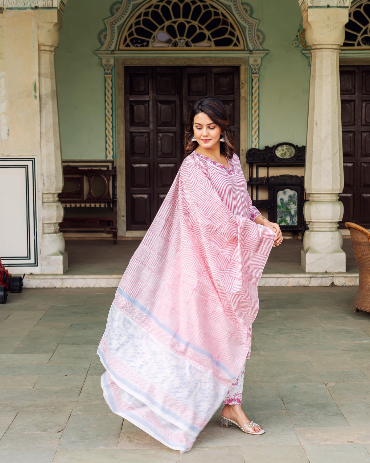 Woman wearing a white and pink striped hand-block-printed kurta with elegance and poise outdoors.